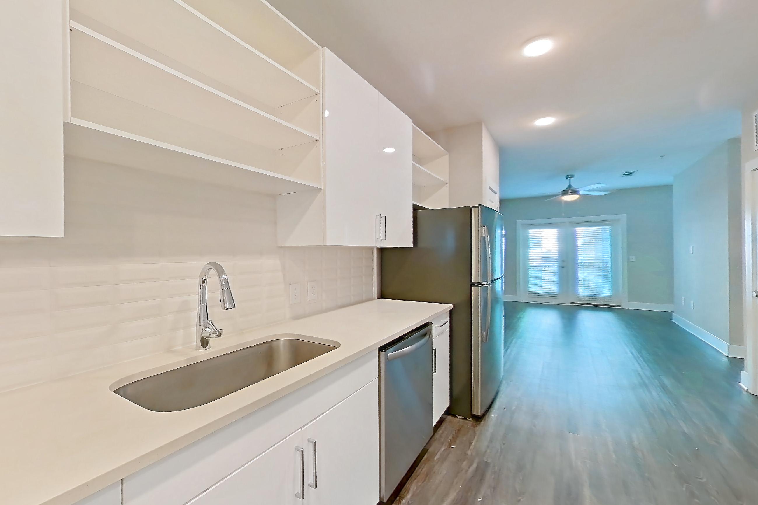 Kitchen with dark wood-finish flooring, dishwasher, electric range, light countertops, microwave, oven/range, refrigerator, and stainless steel appliances, Apartment 1278 at Cortland at the Hill