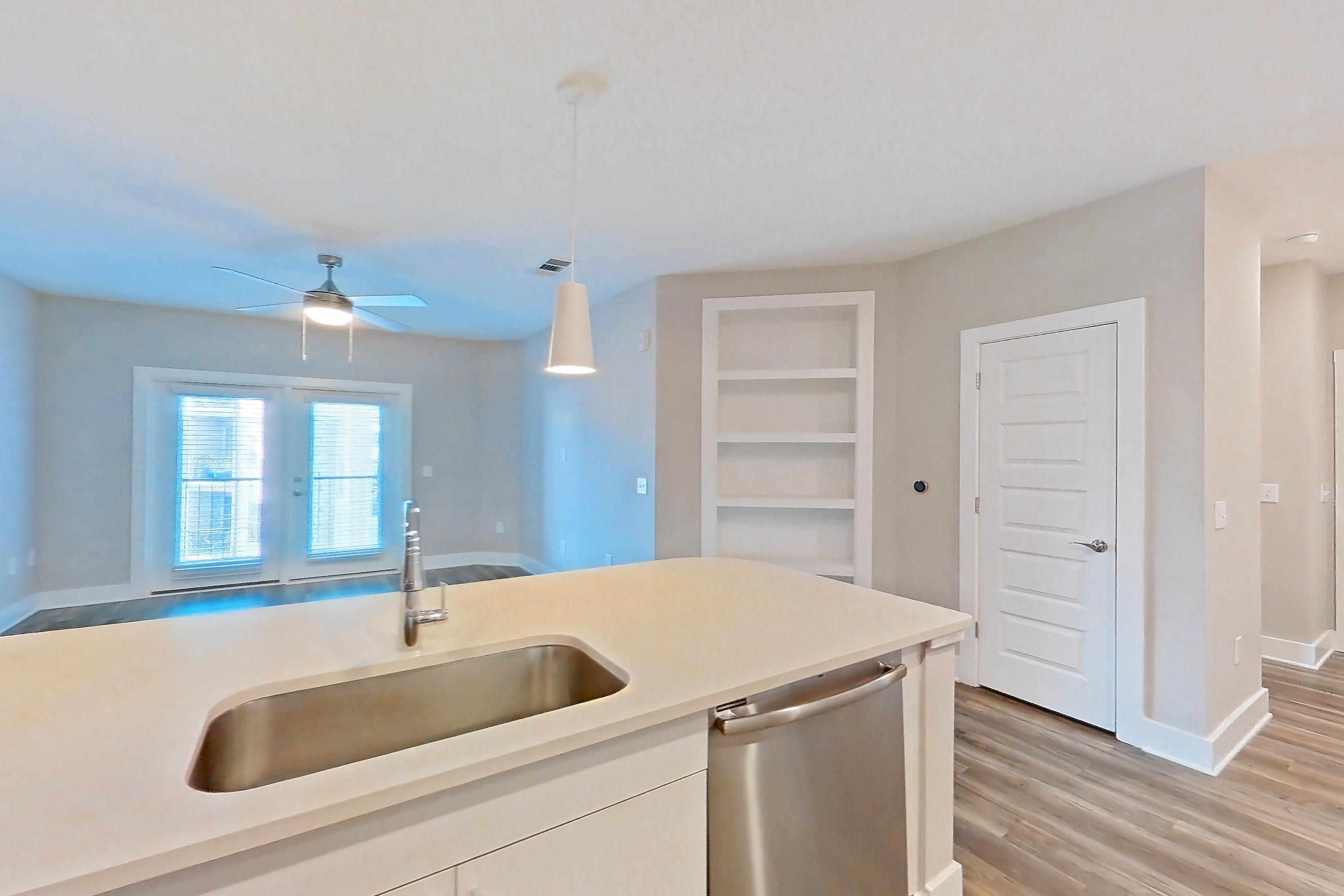 Kitchen with dishwasher, electric range, kitchen island, light countertops, light stone countertops, light wood-finish flooring, microwave, oven/range, refrigerator, and stainless steel appliances, Apartment 1544 at Cortland at the Hill