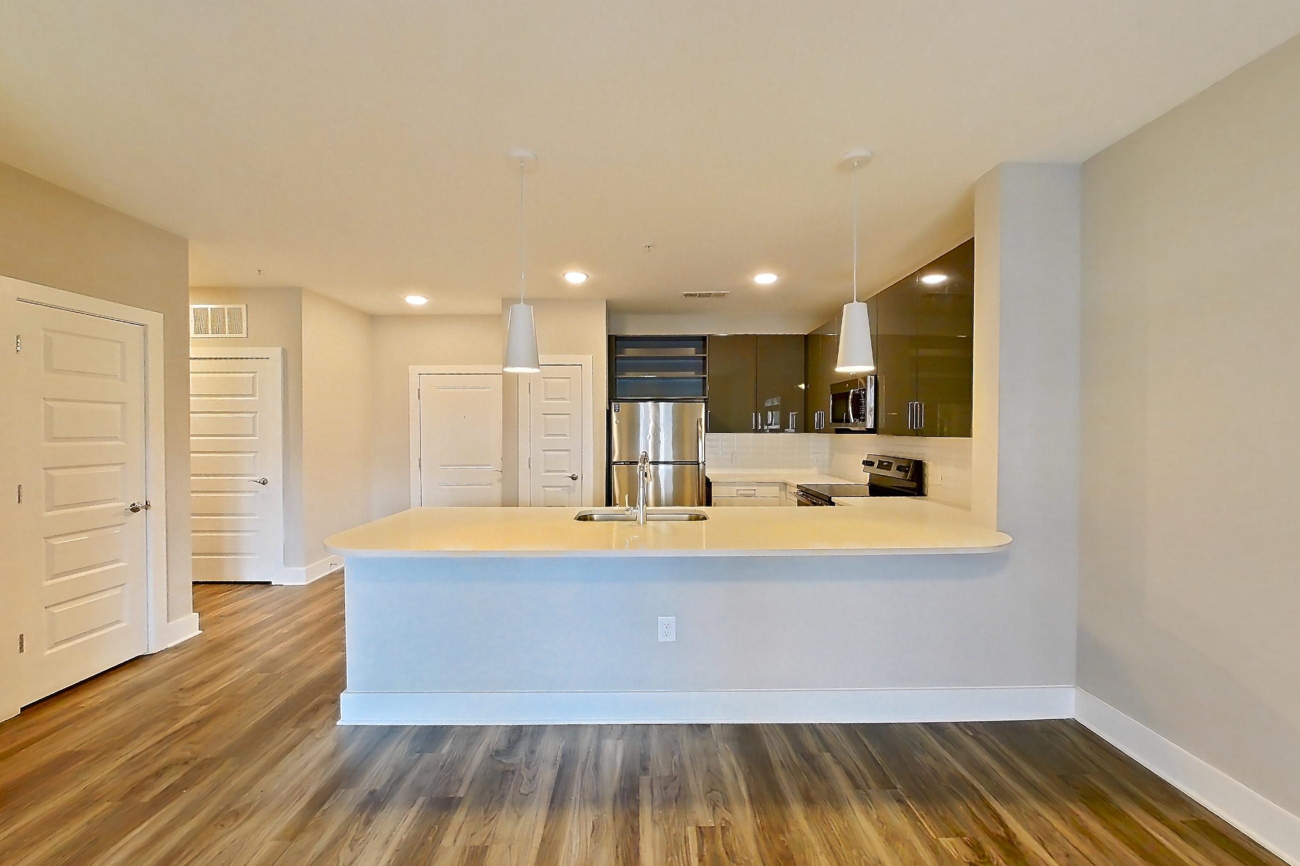 Living room with dark wood-finish flooring, electric range, light countertops, oven/range, refrigerator, and stainless steel appliances, Apartment 1544 at Cortland at the Hill