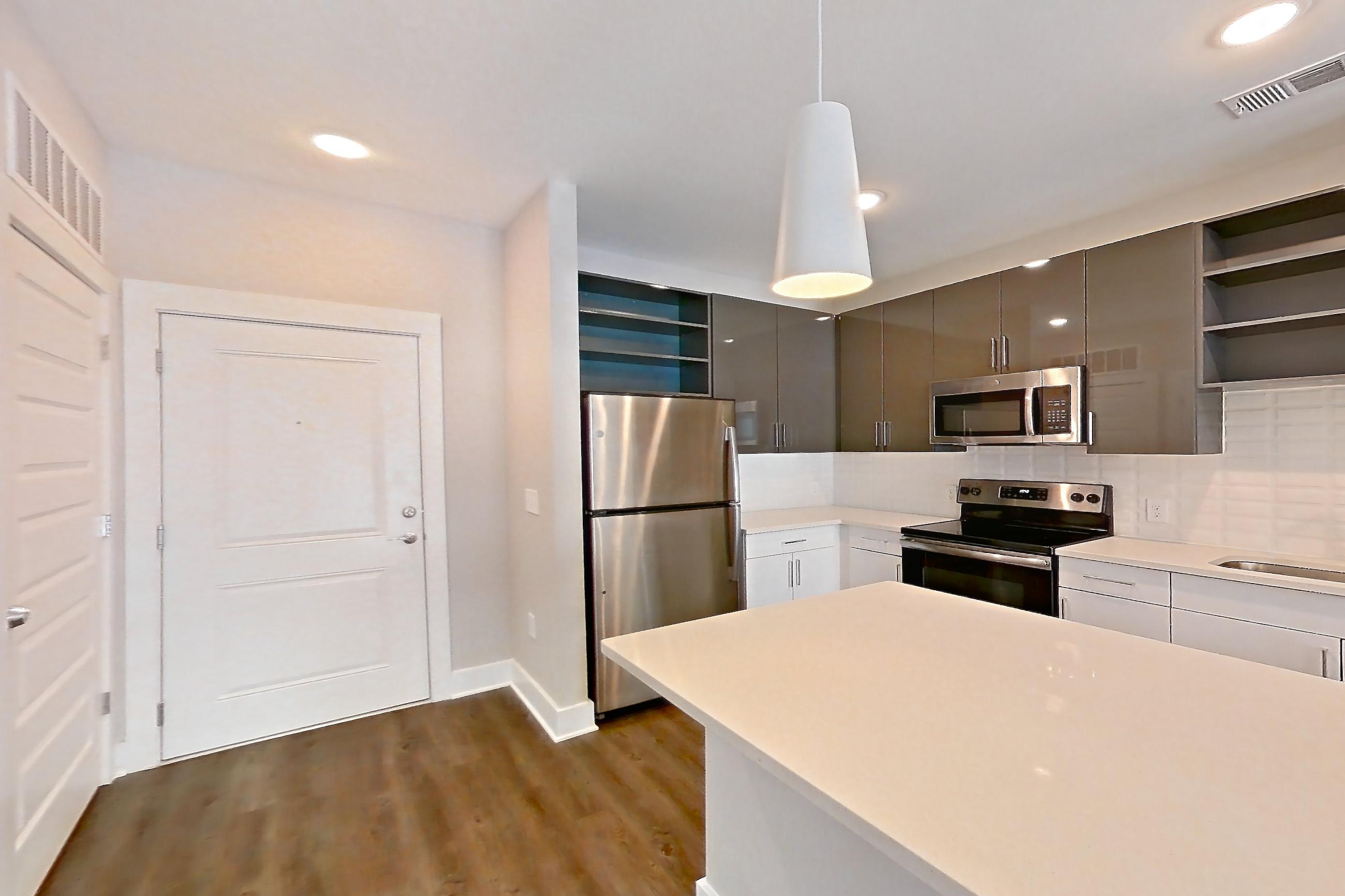 Dining room with dark wood-finish flooring, dishwasher, electric range, light countertops, light stone countertops, microwave, oven/range, refrigerator, and stainless steel appliances, Apartment 1466 at Cortland at the Hill