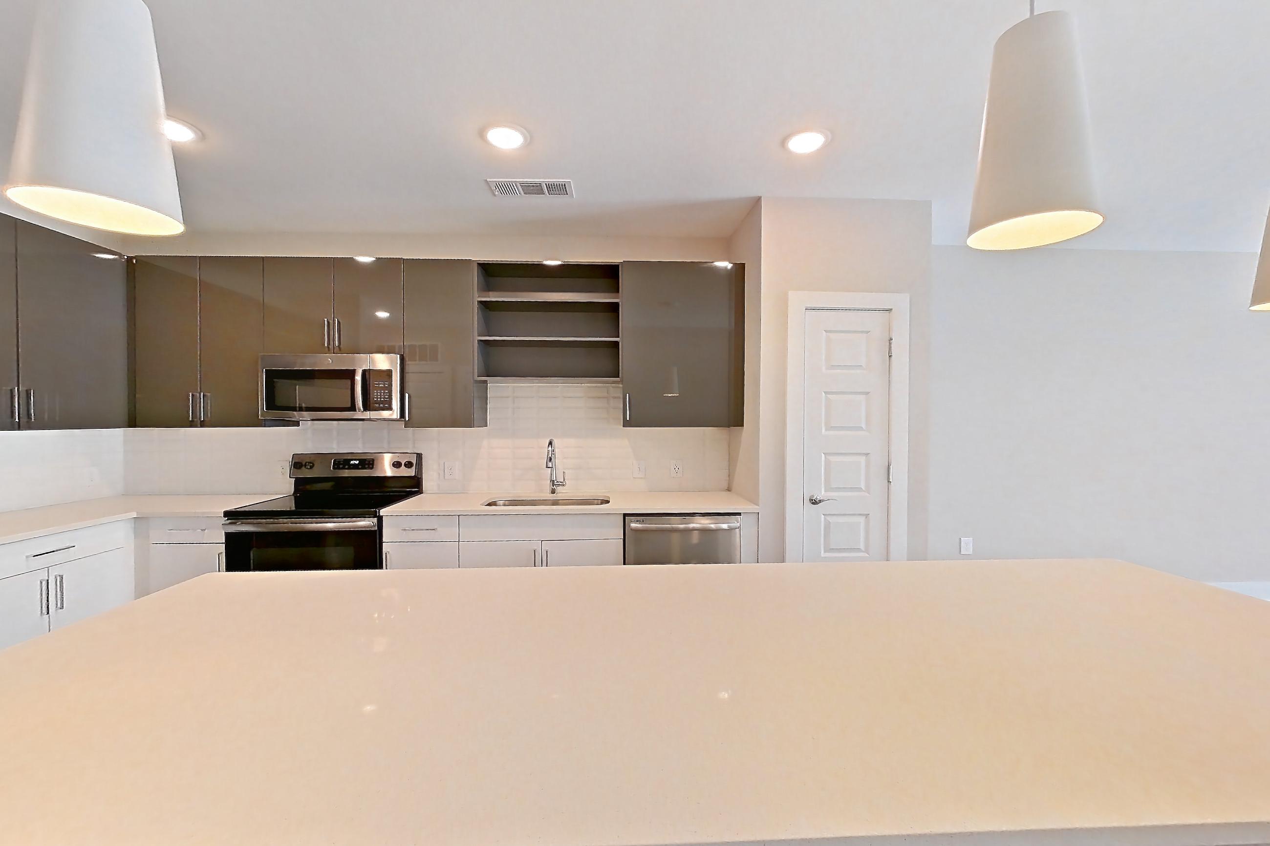 Dining room with dark wood-finish flooring, dishwasher, electric range, light countertops, light stone countertops, microwave, oven/range, refrigerator, and stainless steel appliances, Apartment 1466 at Cortland at the Hill