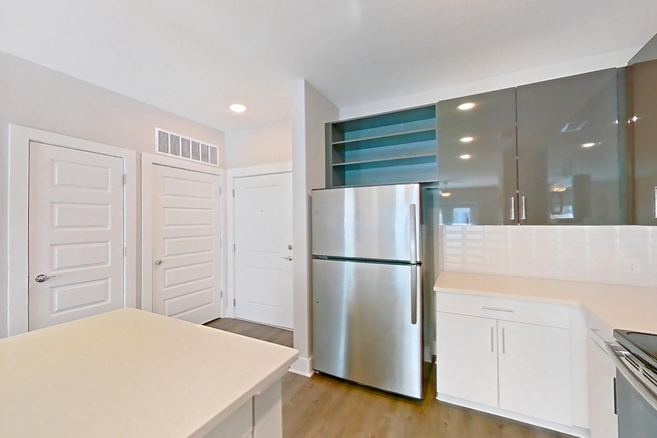 Kitchen with dark wood-finish flooring, dishwasher, electric range, light countertops, light wood-finish flooring, oven/range, refrigerator, and stainless steel appliances, Apartment 1466 at Cortland at the Hill
