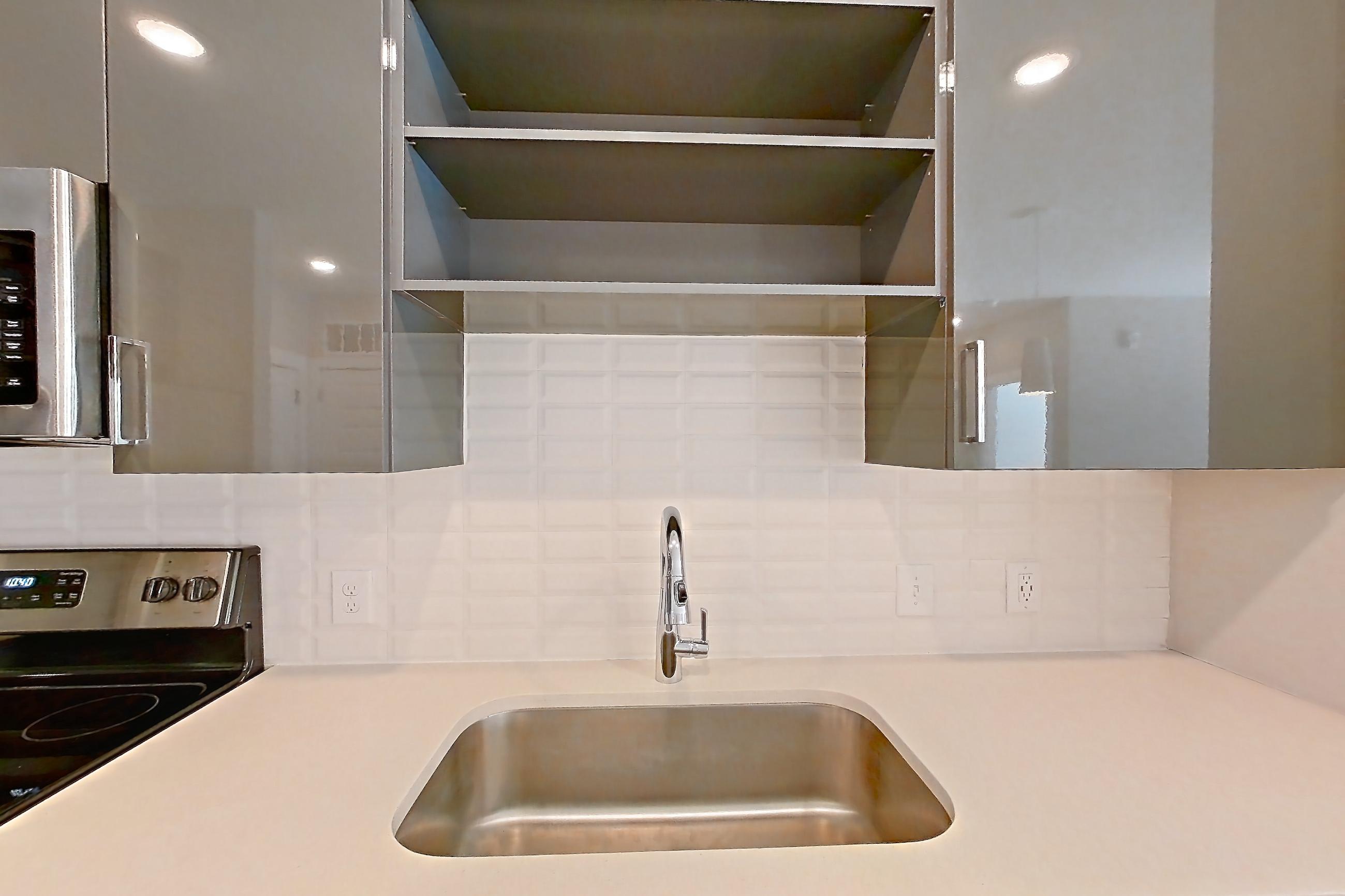 Kitchen with dark wood-finish flooring, dishwasher, electric range, light countertops, light wood-finish flooring, oven/range, refrigerator, and stainless steel appliances, Apartment 1466 at Cortland at the Hill