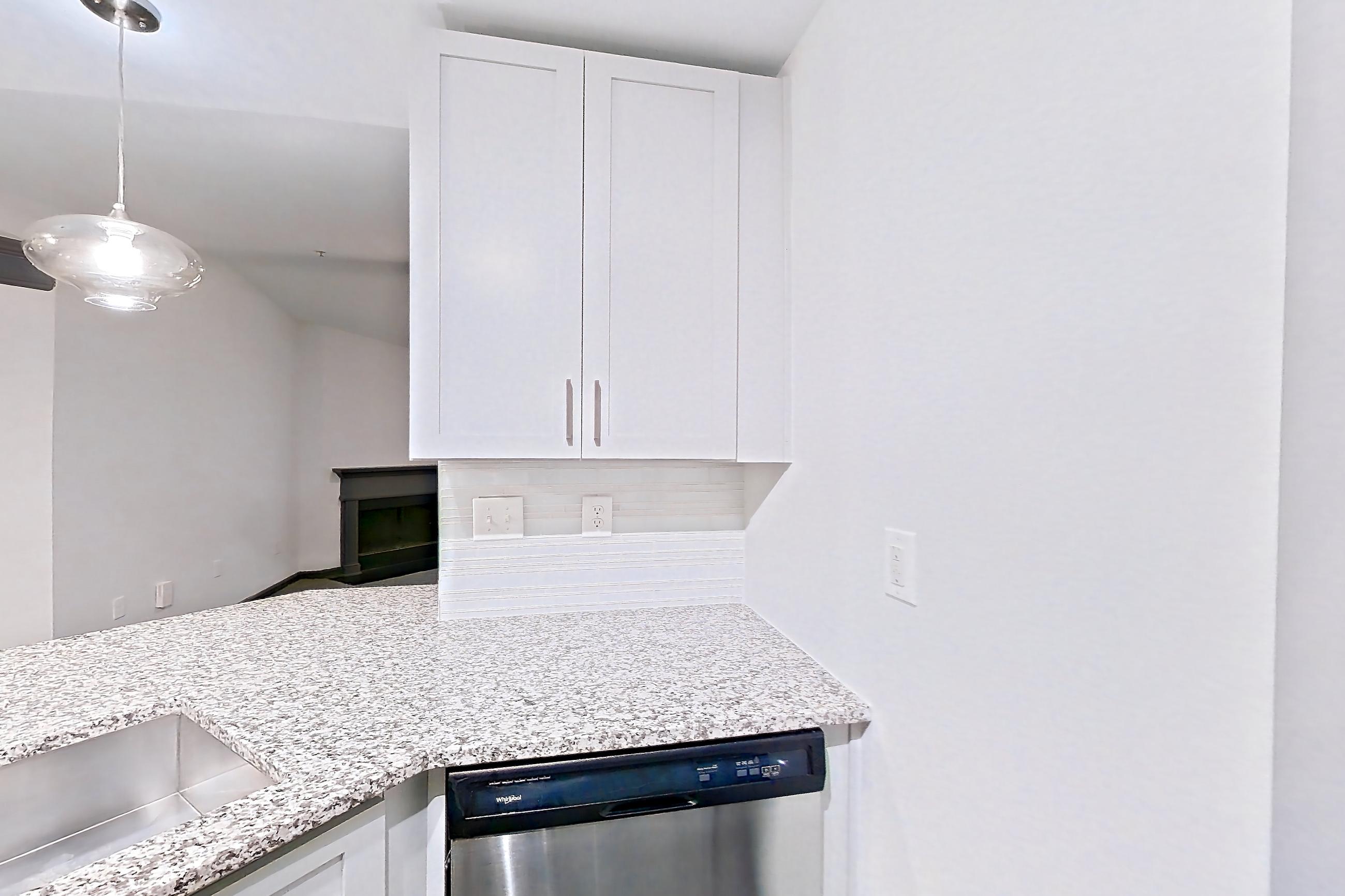 Kitchen with dark wood-finish flooring, dishwasher, electric range, light countertops, light stone countertops, microwave, oven/range, and stainless steel appliances, Apartment 2524 at Cortland Duluth