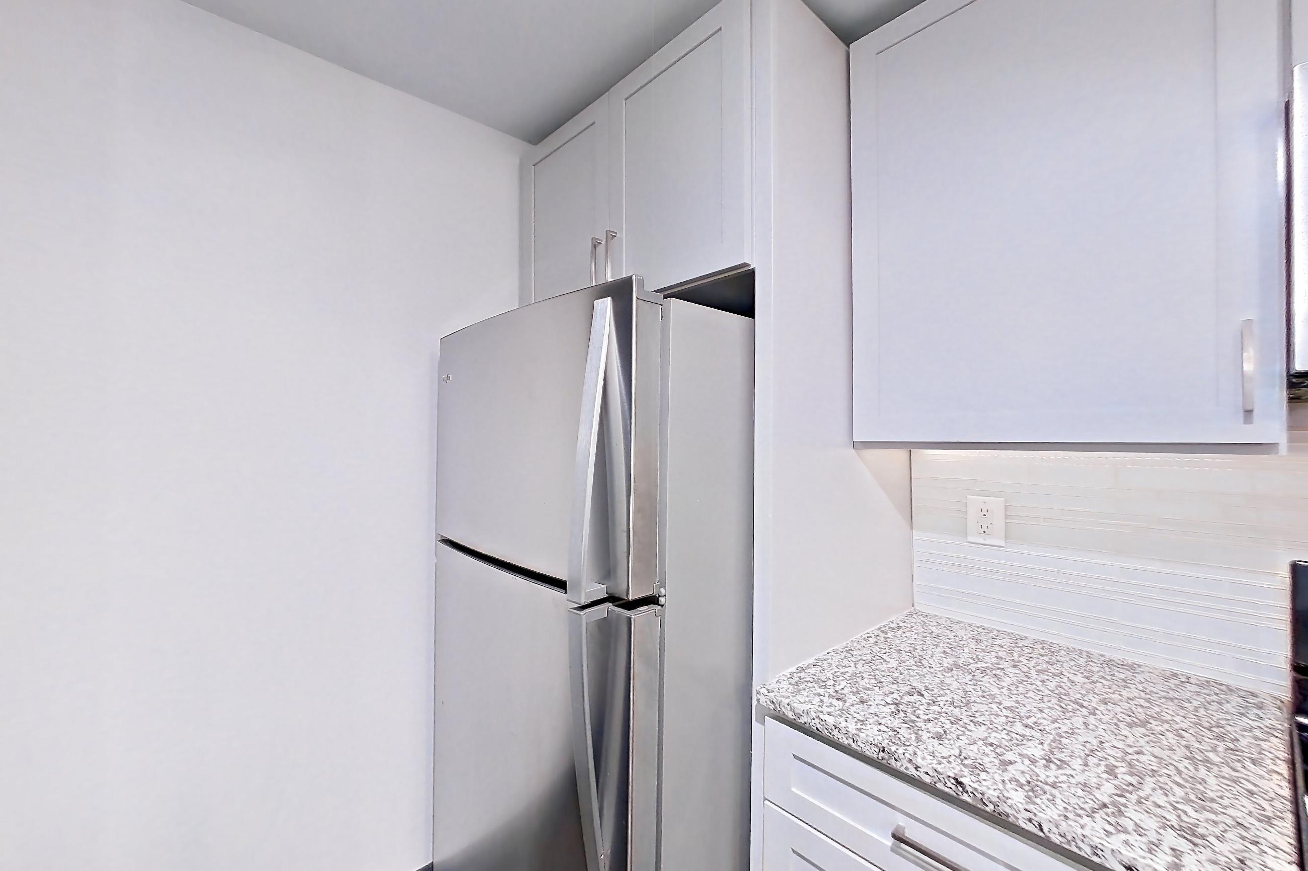 Kitchen with dark wood-finish flooring, dishwasher, electric range, light countertops, light stone countertops, microwave, oven/range, and stainless steel appliances, Apartment 2524 at Cortland Duluth