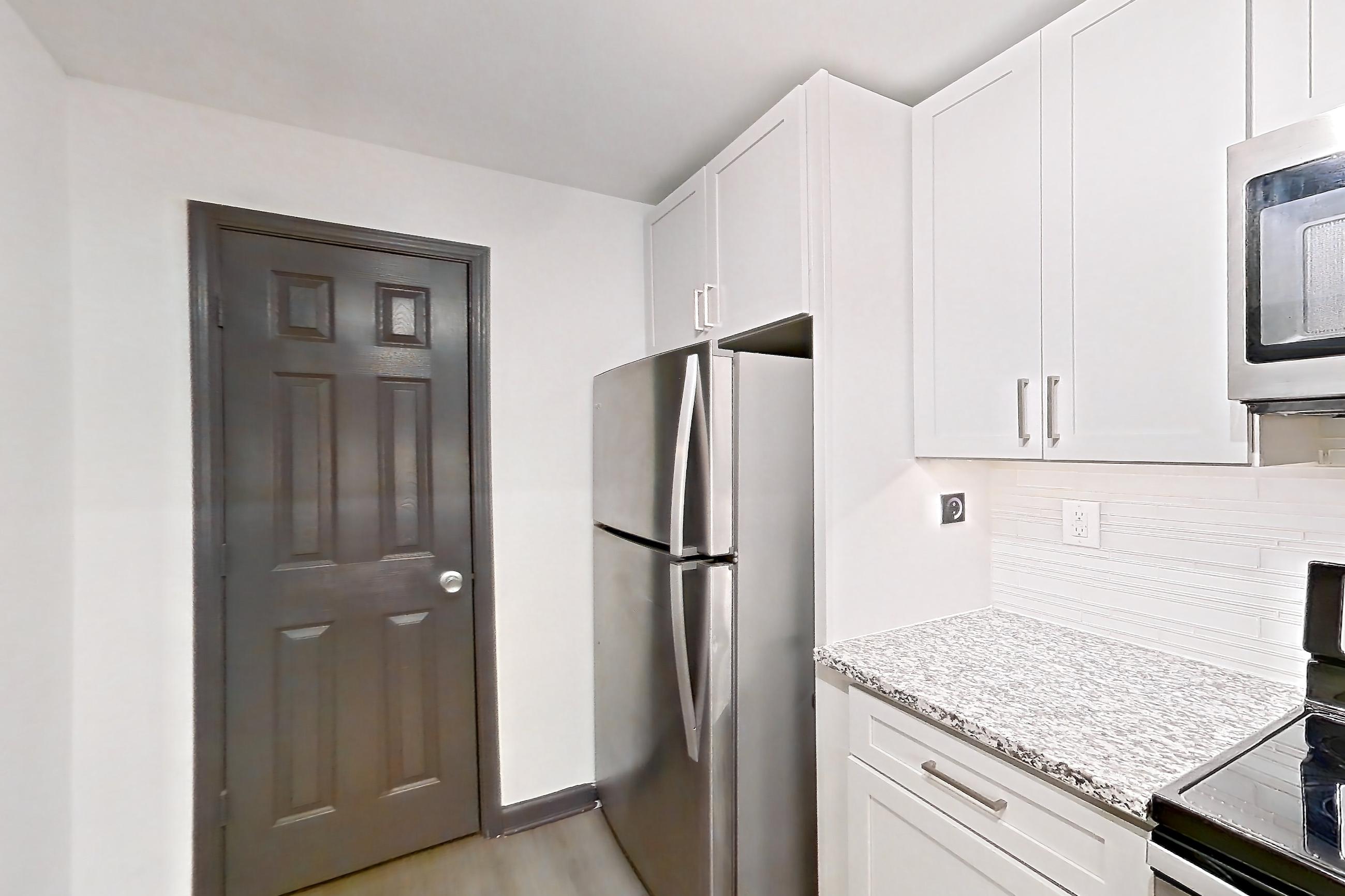Kitchen with dishwasher, electric range, light countertops, light stone countertops, light wood-finish flooring, microwave, oven/range, refrigerator, and stainless steel appliances, Apartment 2924 at Cortland Duluth