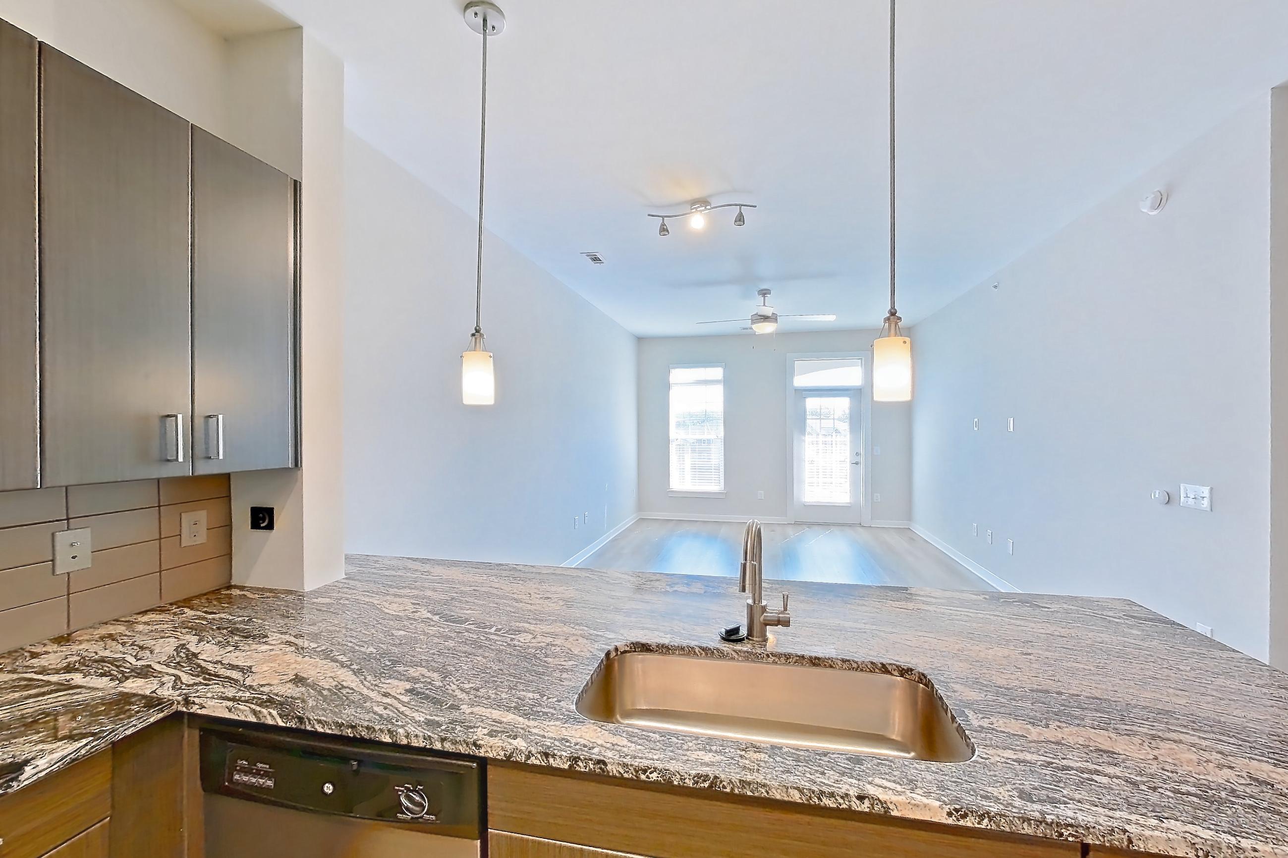 Kitchen with dark stone countertops, dishwasher, electric range, light stone countertops, light wood-finish flooring, microwave, oven/range, refrigerator, stainless steel appliances, and water & ice dispenser, Apartment 8305 at Cortland Wren Northlake