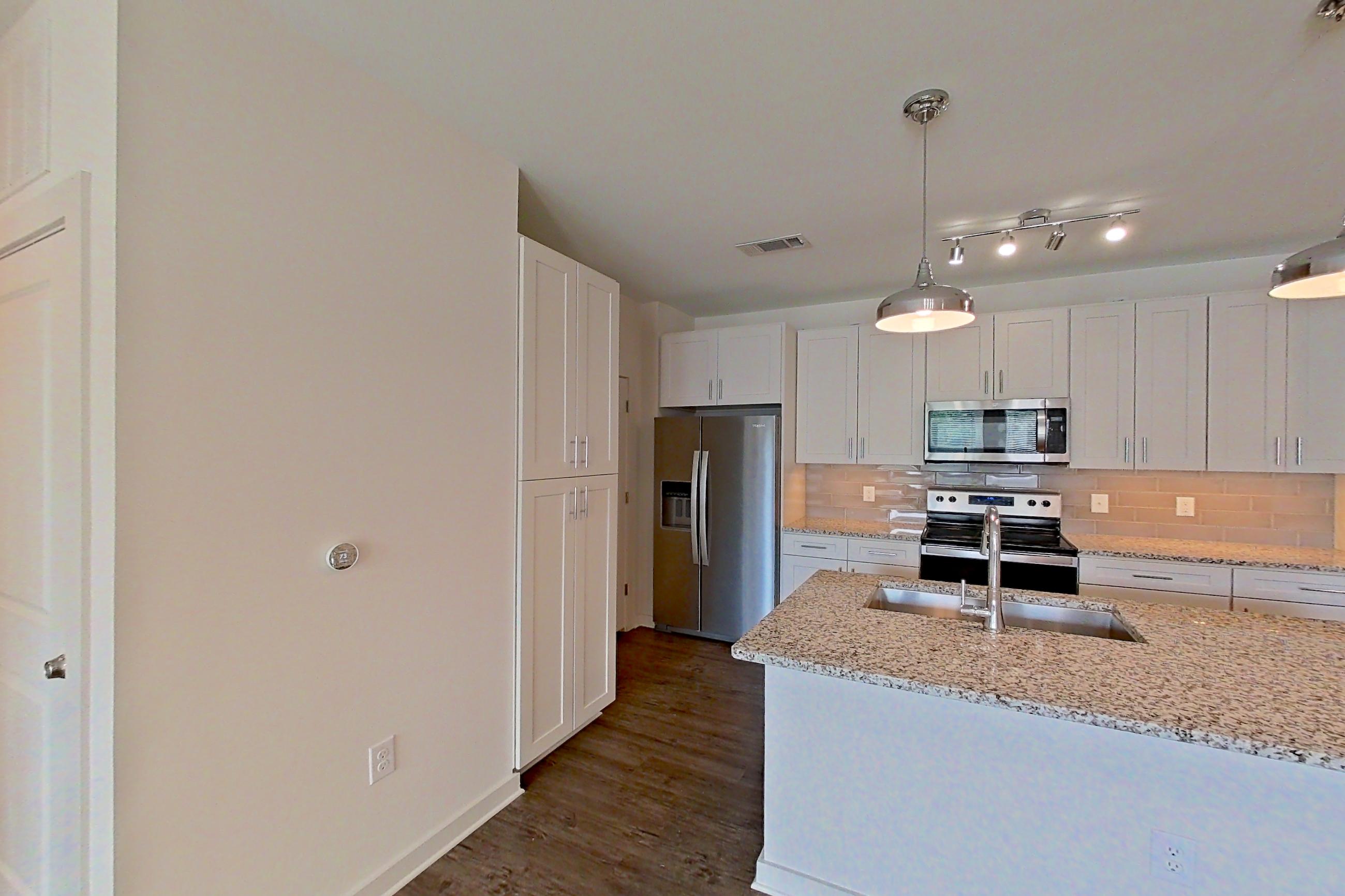 Dining room with dark wood-finish flooring, electric range, light countertops, light stone countertops, microwave, oven/range, refrigerator, stainless steel appliances, and water & ice dispenser, Apartment 3-209 at Cortland Wren Northlake
