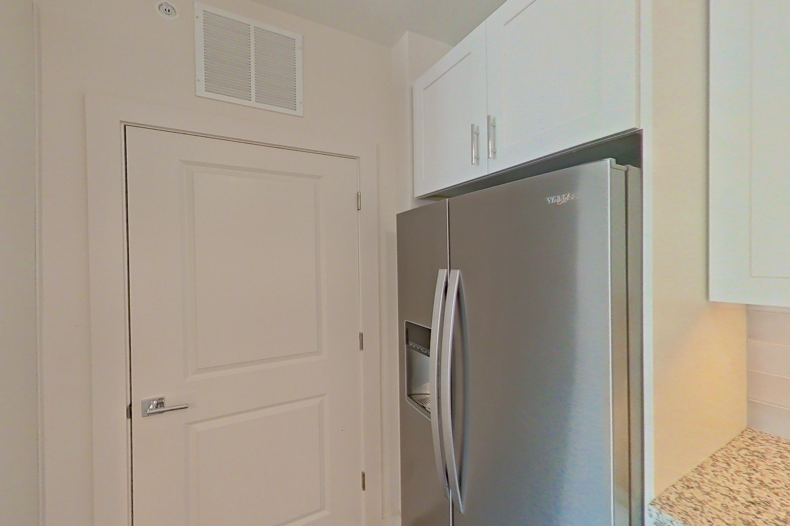 Kitchen with black appliances, dark wood-finish flooring, electric range, kitchen island, light countertops, light stone countertops, microwave, oven/range, refrigerator, stainless steel appliances, and water & ice dispenser, Apartment 3-209 at Cortland Wren Northlake