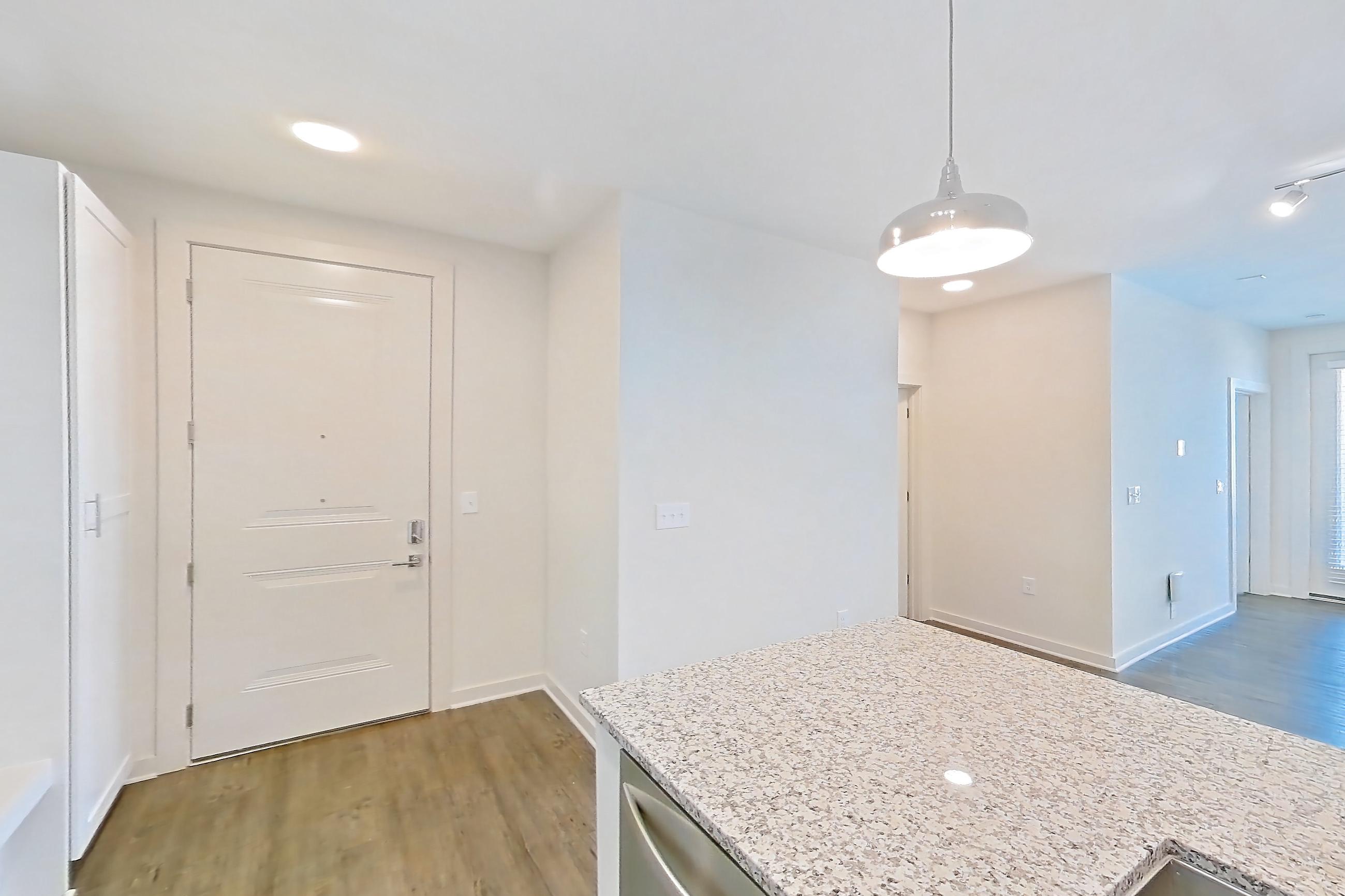 Kitchen with dark wood-finish flooring, dishwasher, electric range, kitchen island, light stone countertops, oven/range, and stainless steel appliances, Apartment 5-209 at Cortland Wren Northlake