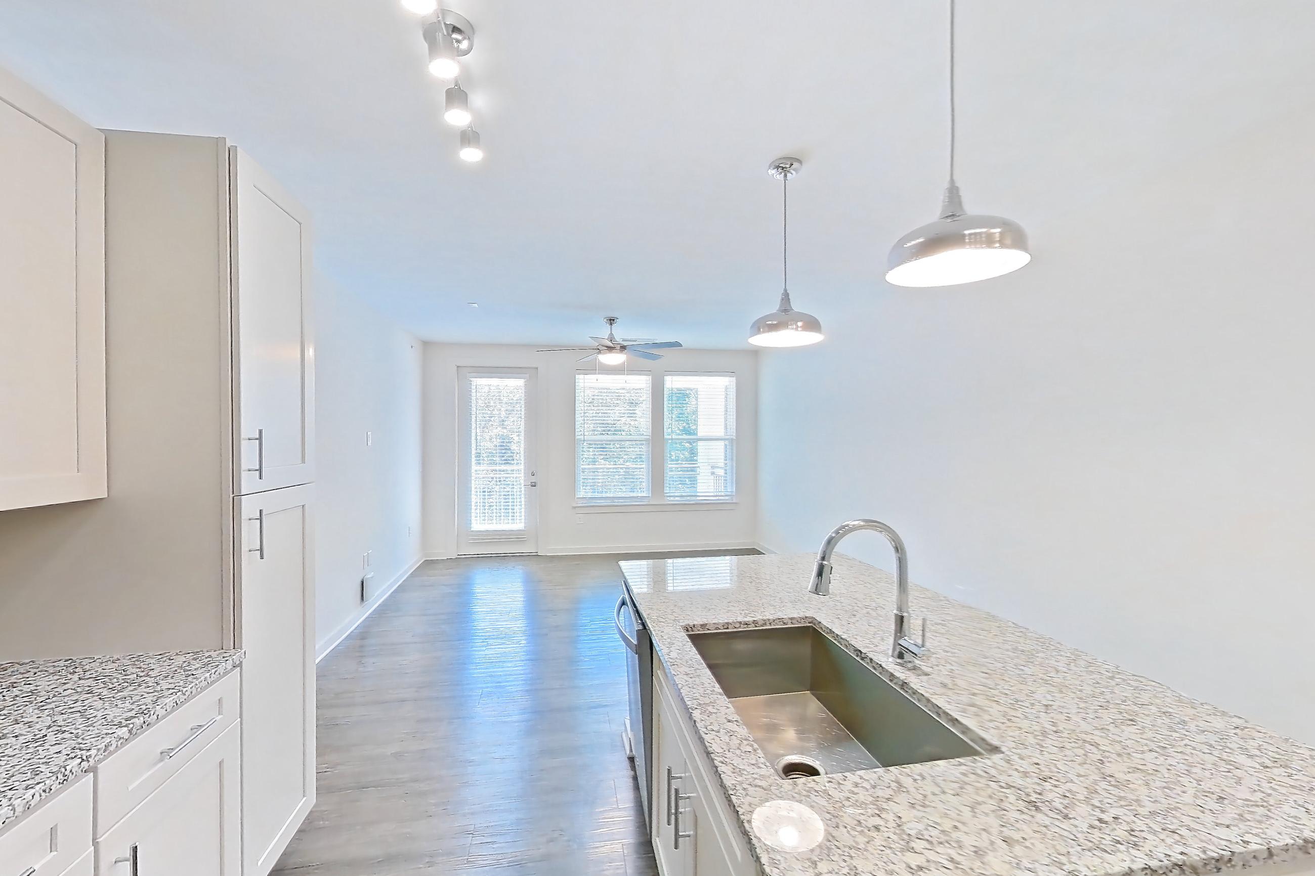 Kitchen with dark wood-finish flooring, electric range, kitchen island, light countertops, light stone countertops, microwave, oven/range, refrigerator, and stainless steel appliances, Apartment 5-310 at Cortland Wren Northlake