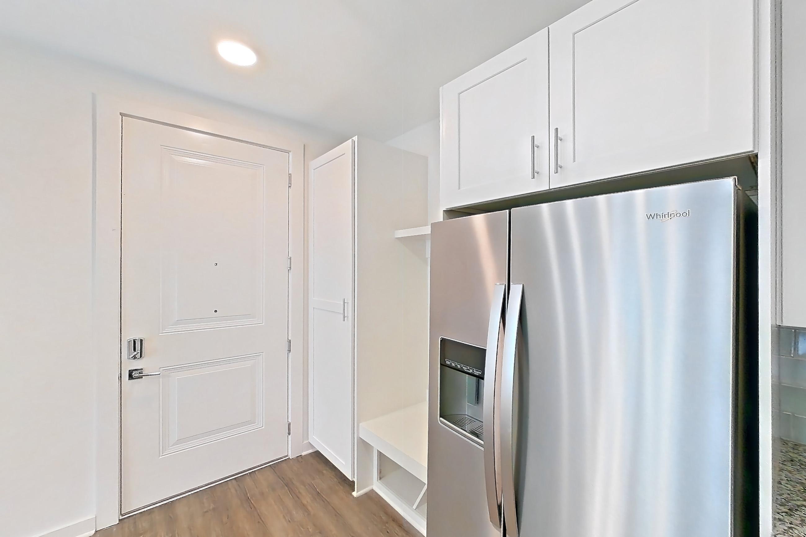 Kitchen with dark wood-finish flooring, electric range, kitchen island, light countertops, light stone countertops, microwave, oven/range, refrigerator, and stainless steel appliances, Apartment 5-310 at Cortland Wren Northlake