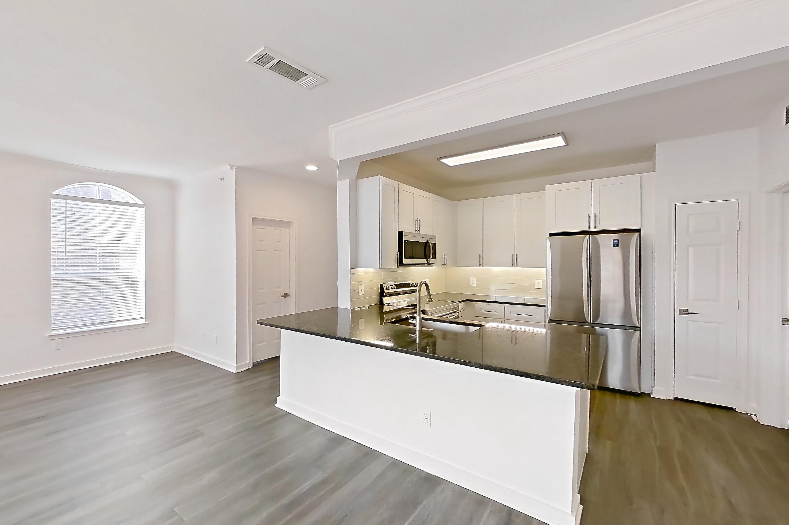 Dining room with dark stone countertops, dark wood-finish flooring, light countertops, microwave, oven/range, refrigerator, and stainless steel appliances, Apartment 00328 at Cortland West Plano