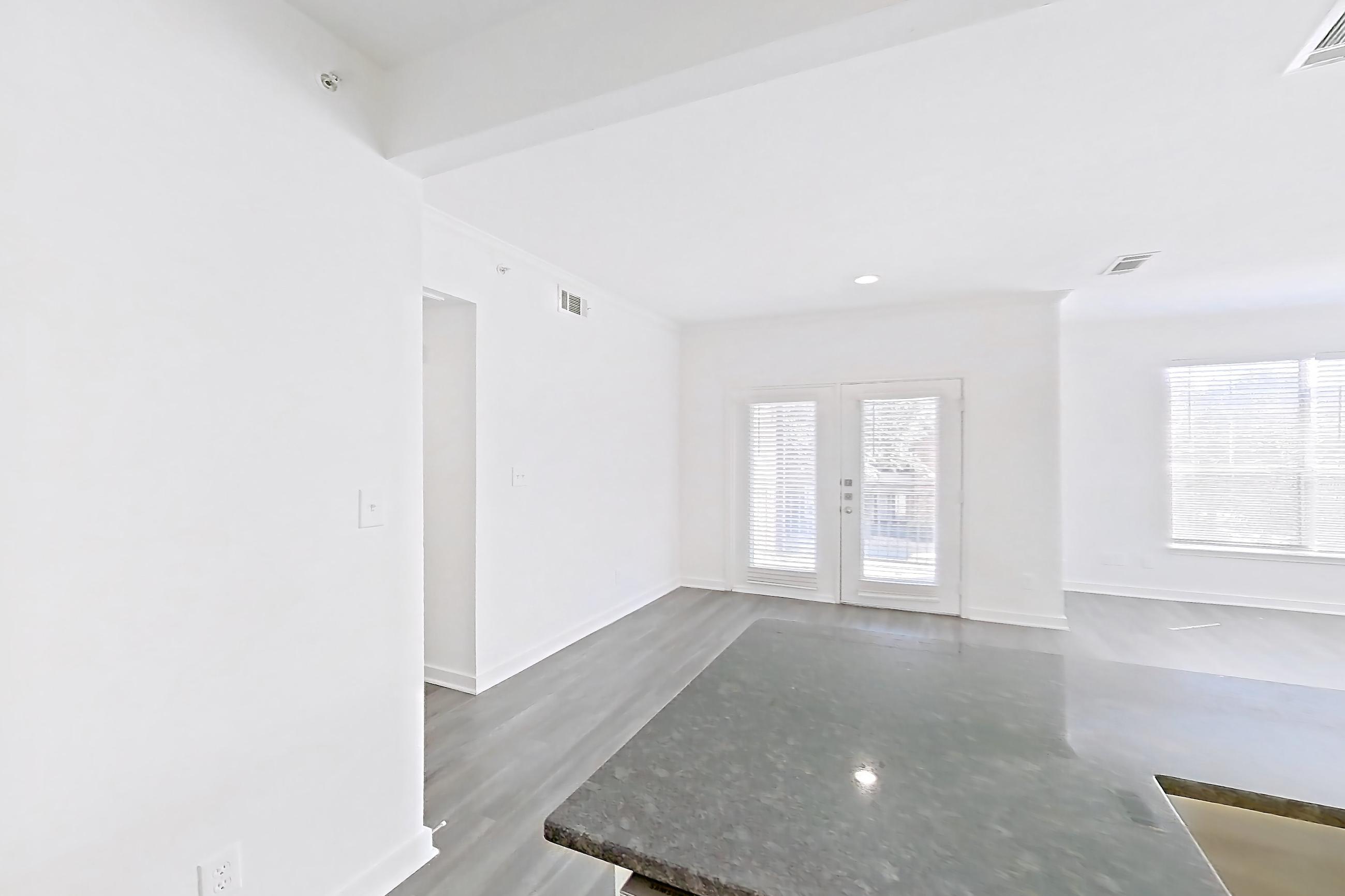 Kitchen with dark stone countertops, dark wood-finish flooring, dishwasher, electric range, kitchen island, light countertops, microwave, oven/range, refrigerator, and stainless steel appliances, Apartment 00328 at Cortland West Plano