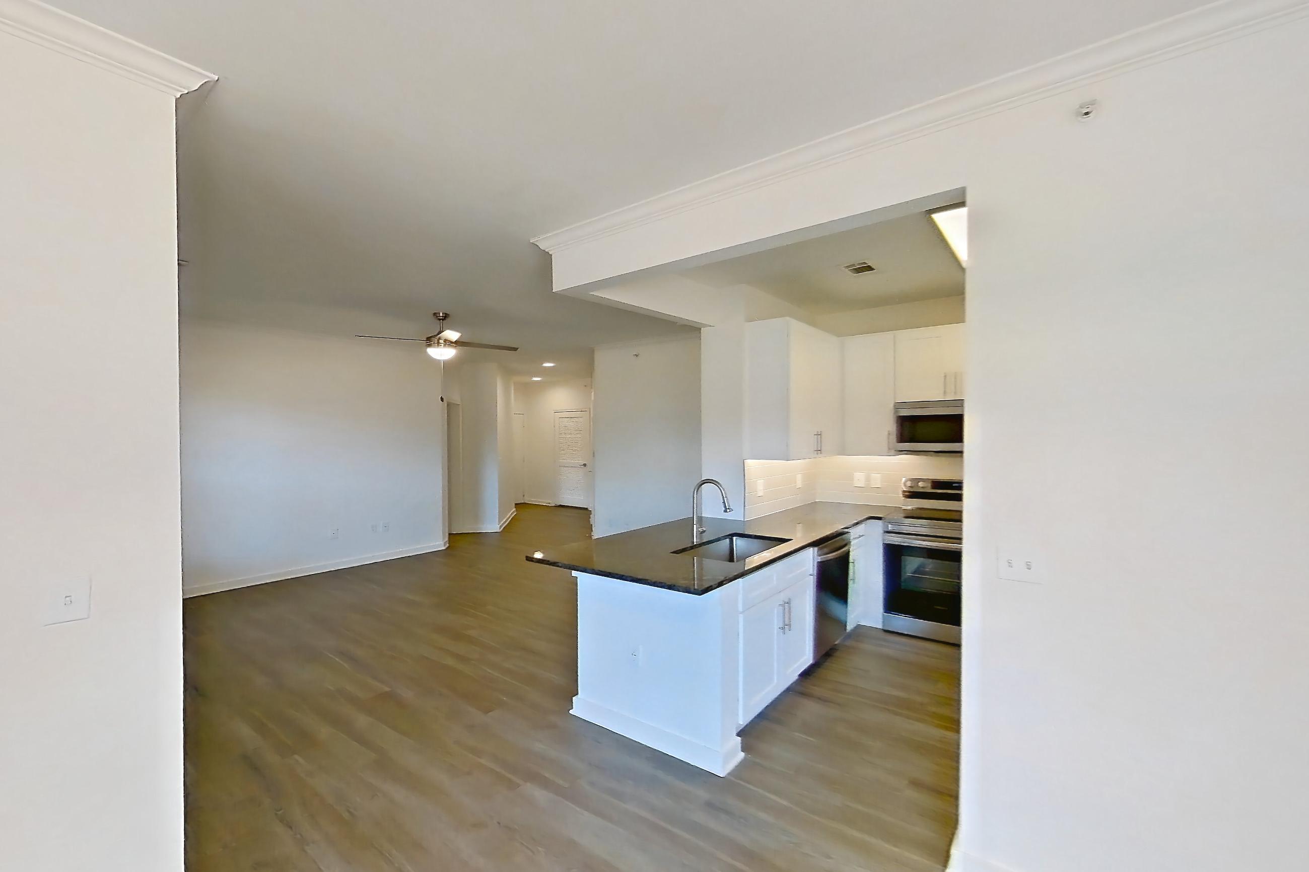 Dining room with dark stone countertops, dark wood-finish flooring, dishwasher, electric range, oven/range, and stainless steel appliances, Apartment 02714 at Cortland West Plano
