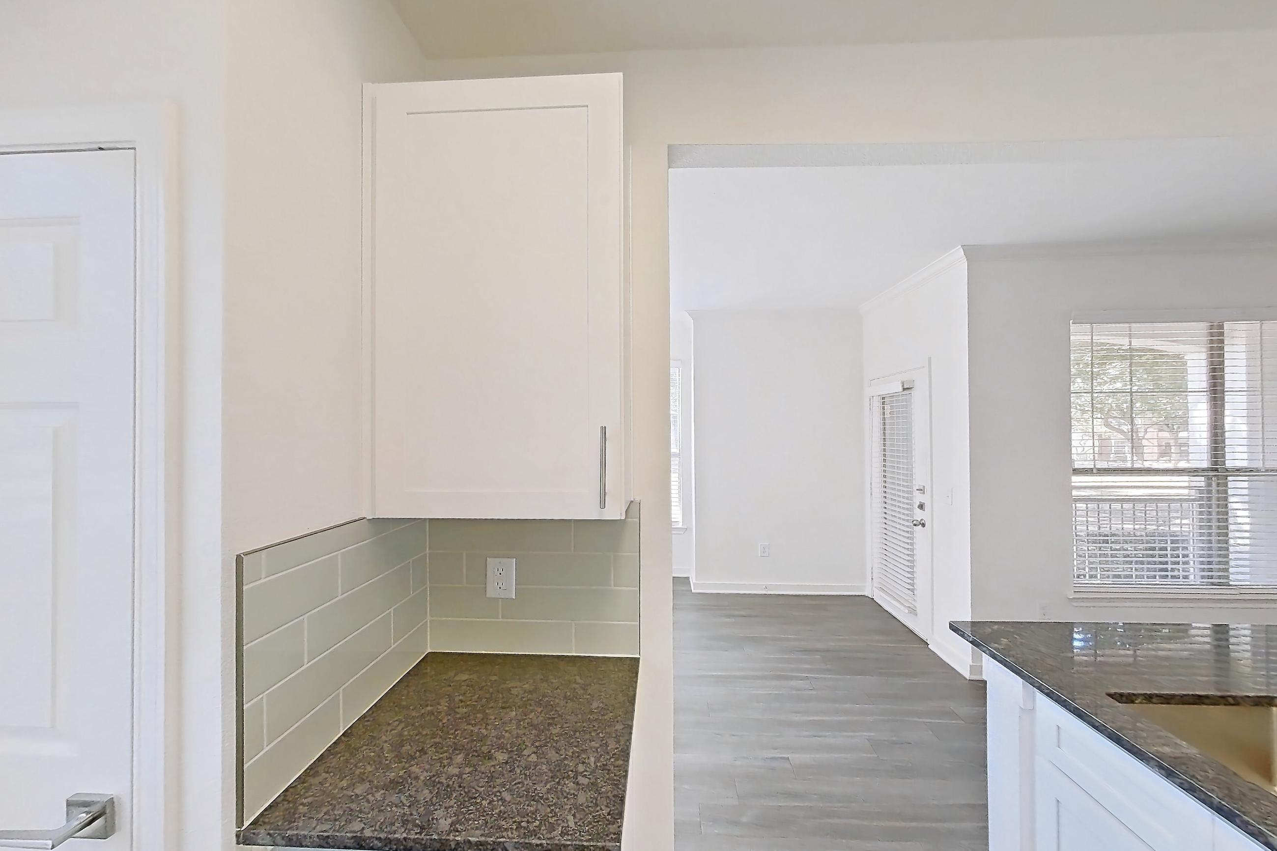 Kitchen with dark stone countertops, dark wood-finish flooring, dishwasher, electric range, oven/range, refrigerator, and stainless steel appliances, Apartment 02714 at Cortland West Plano