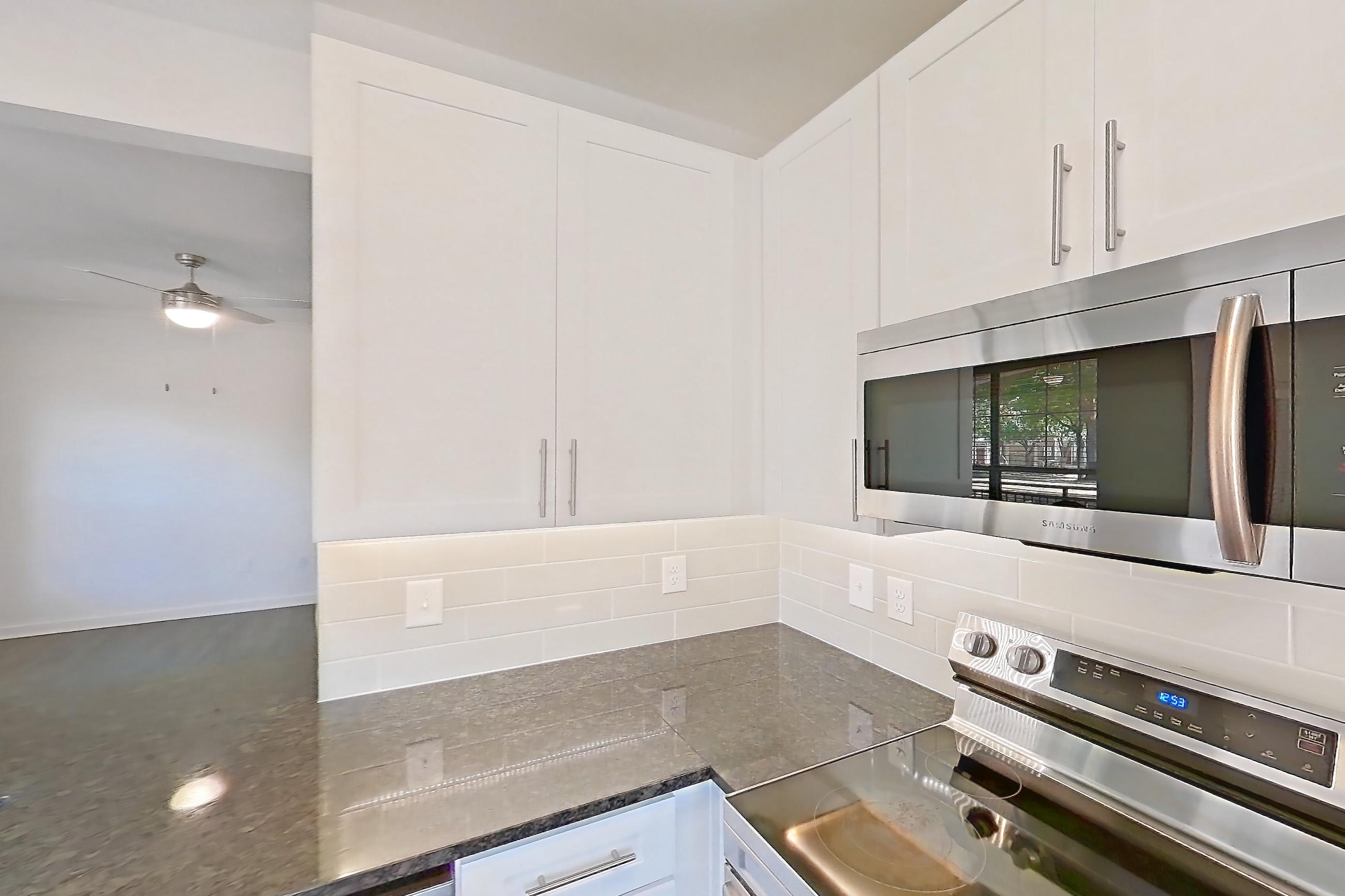 Kitchen with dark stone countertops, dark wood-finish flooring, dishwasher, electric range, oven/range, refrigerator, and stainless steel appliances, Apartment 02714 at Cortland West Plano