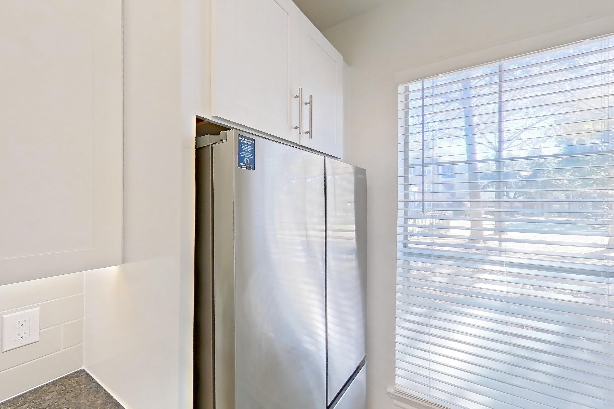 Kitchen with dark stone countertops, dark wood-finish flooring, dishwasher, electric range, oven/range, refrigerator, and stainless steel appliances, Apartment 02714 at Cortland West Plano
