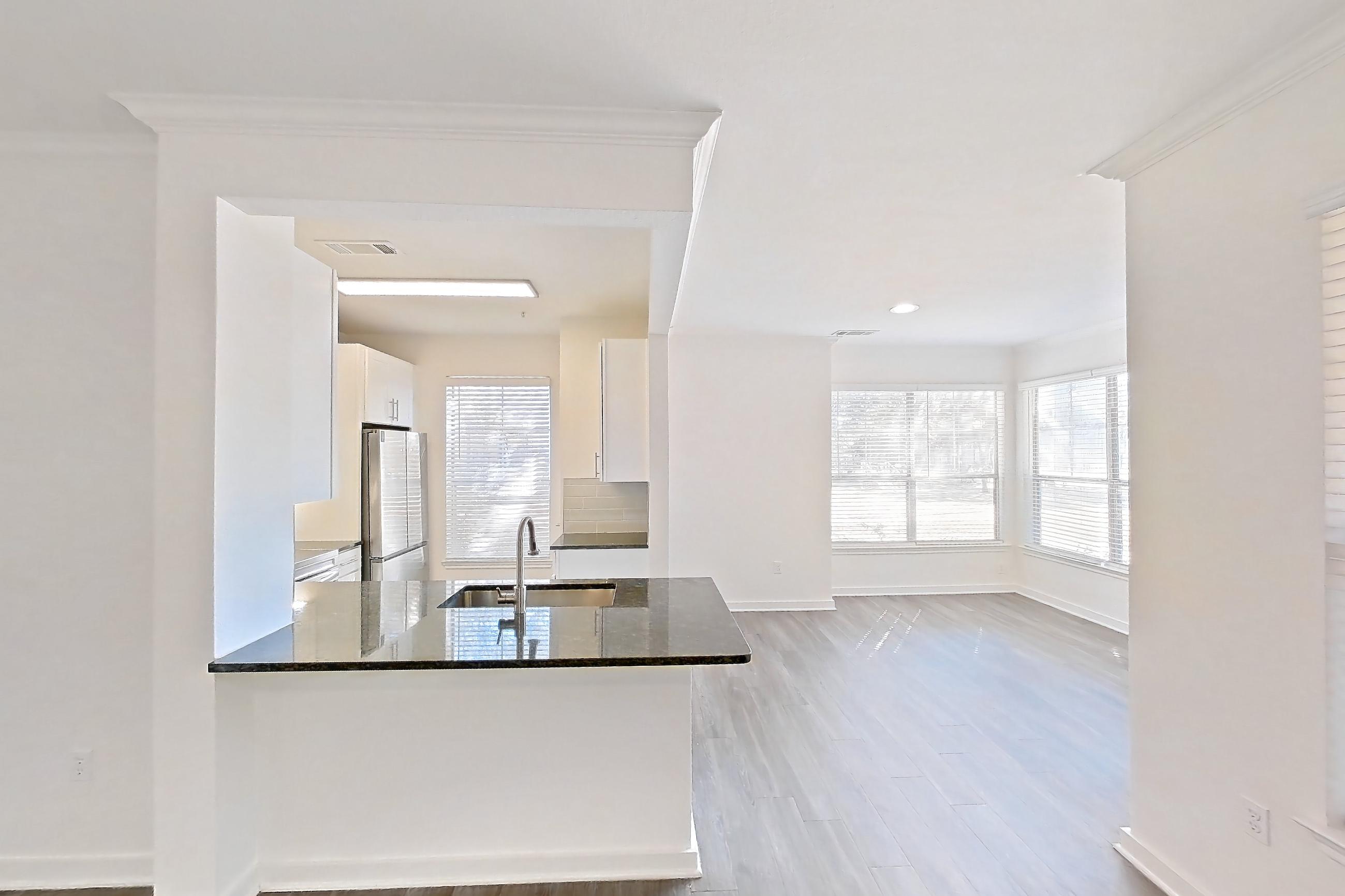 Living room with dark stone countertops and dark wood-finish flooring, Apartment 02714 at Cortland West Plano