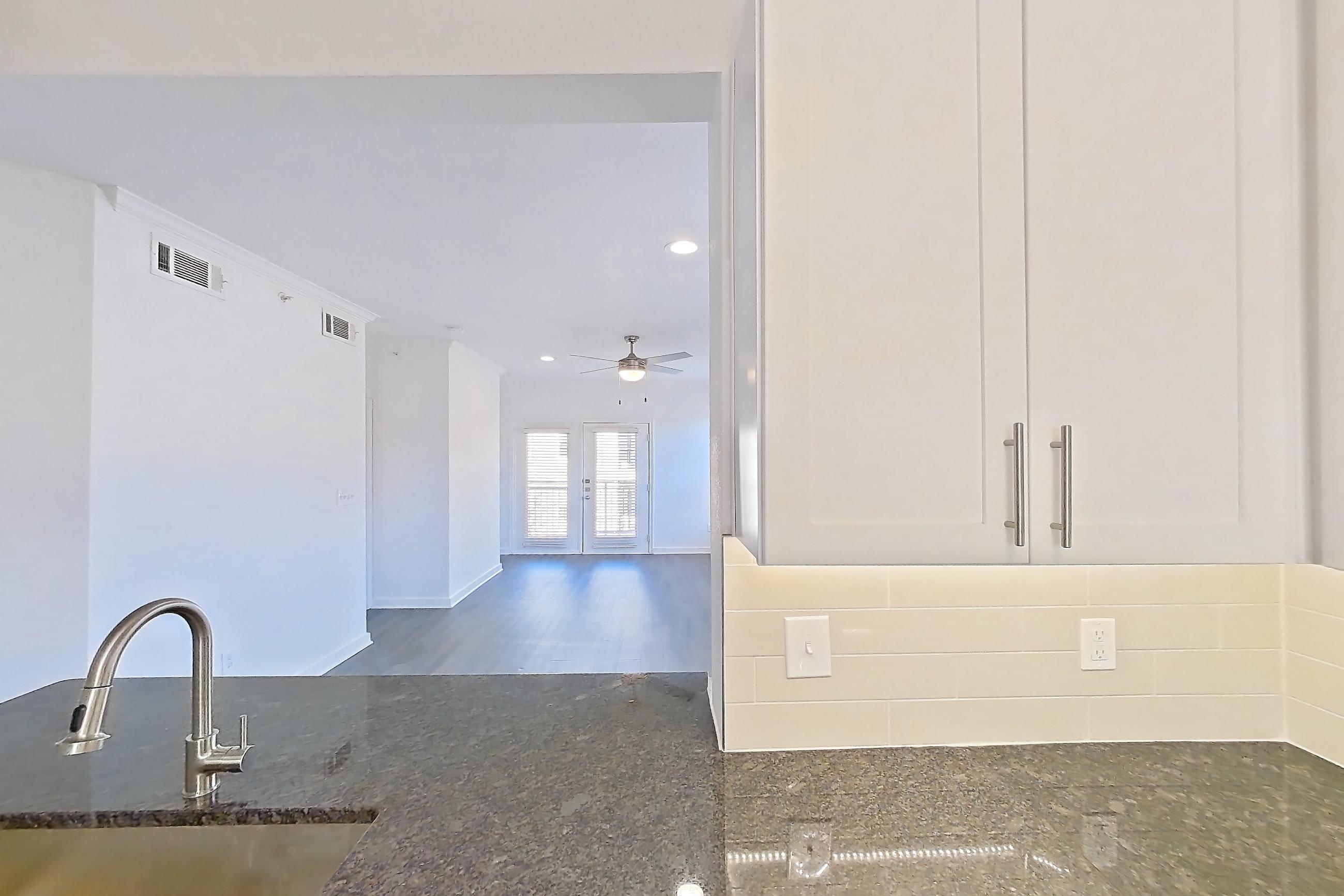 Kitchen with dark stone countertops, dark wood-finish flooring, dishwasher, electric range, light countertops, microwave, oven/range, and stainless steel appliances, Apartment 02831 at Cortland West Plano