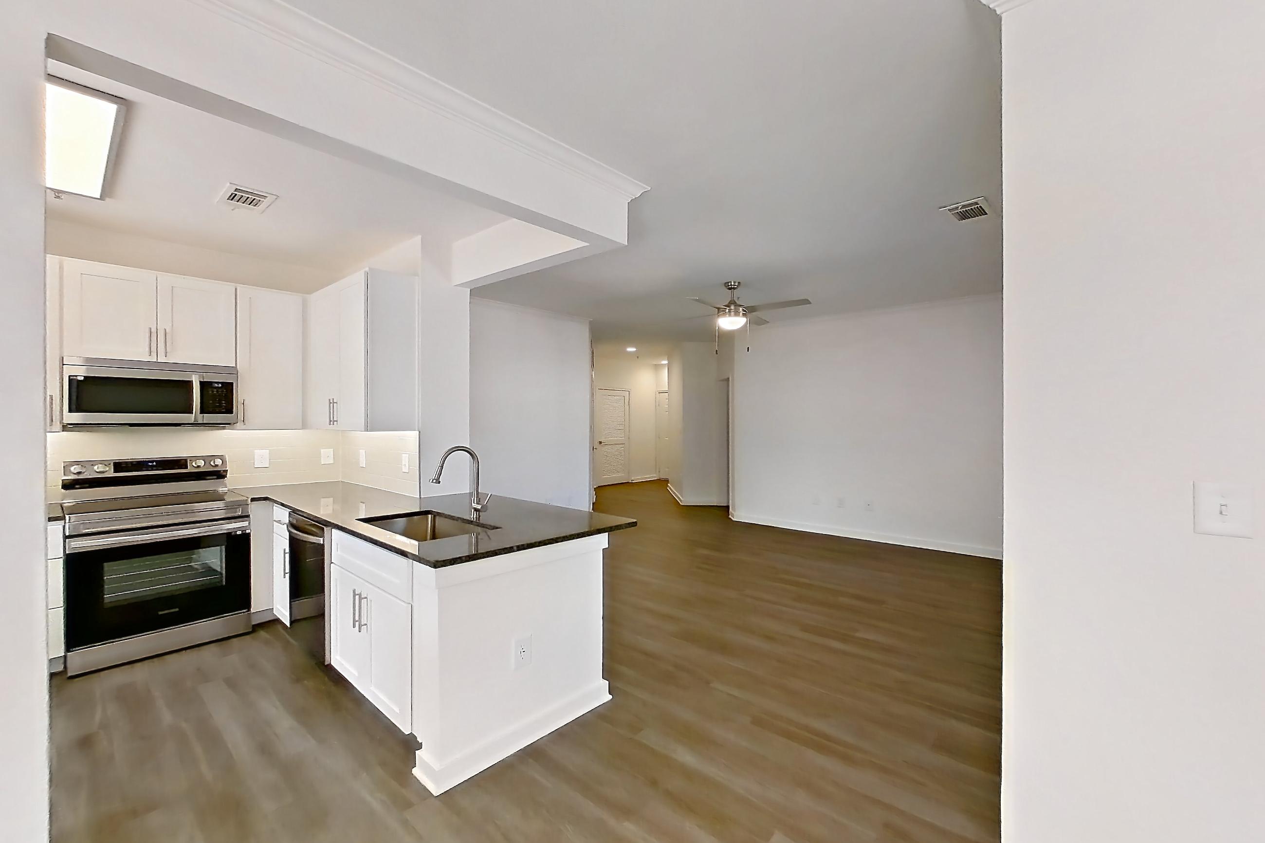 Dining room with dark stone countertops, dark wood-finish flooring, dishwasher, electric range, oven/range, and stainless steel appliances, Apartment 03025 at Cortland West Plano