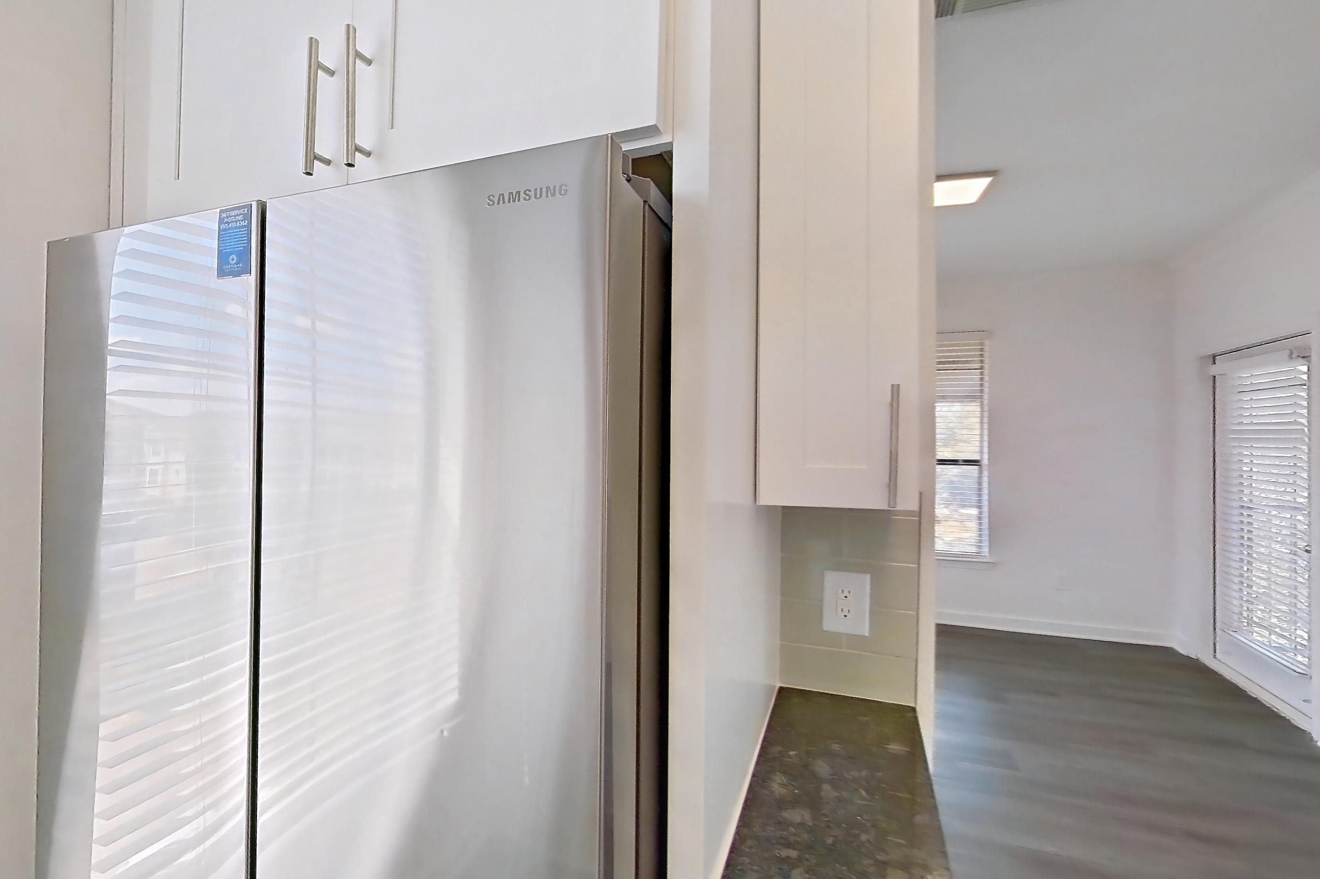 Kitchen with dark stone countertops, dark wood-finish flooring, dishwasher, electric range, light countertops, microwave, oven/range, refrigerator, and stainless steel appliances, Apartment 06301 at Cortland West Plano