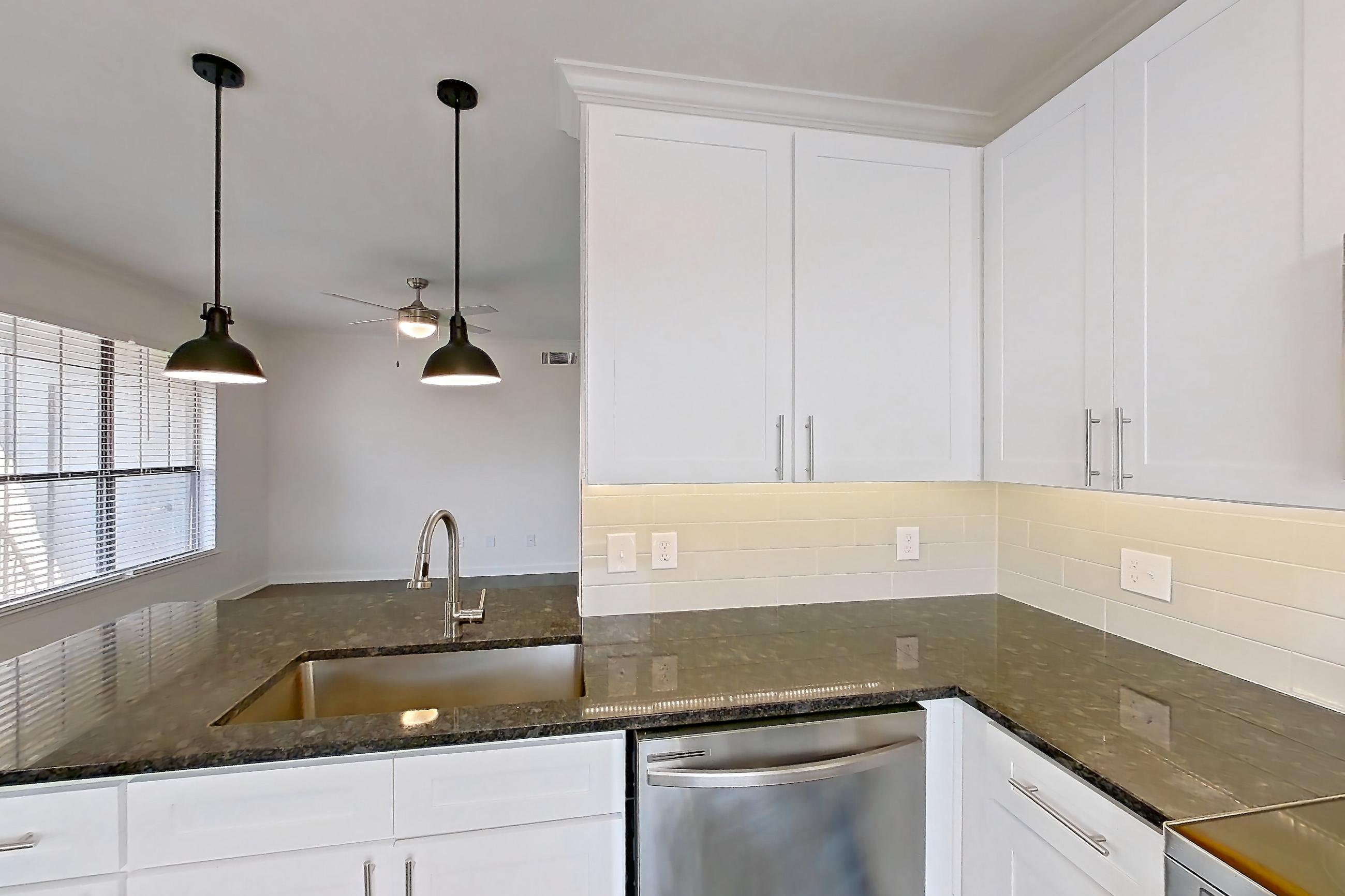 Kitchen with dark stone countertops, dark wood-finish flooring, dishwasher, electric range, light countertops, microwave, oven/range, refrigerator, and stainless steel appliances, Apartment 06301 at Cortland West Plano