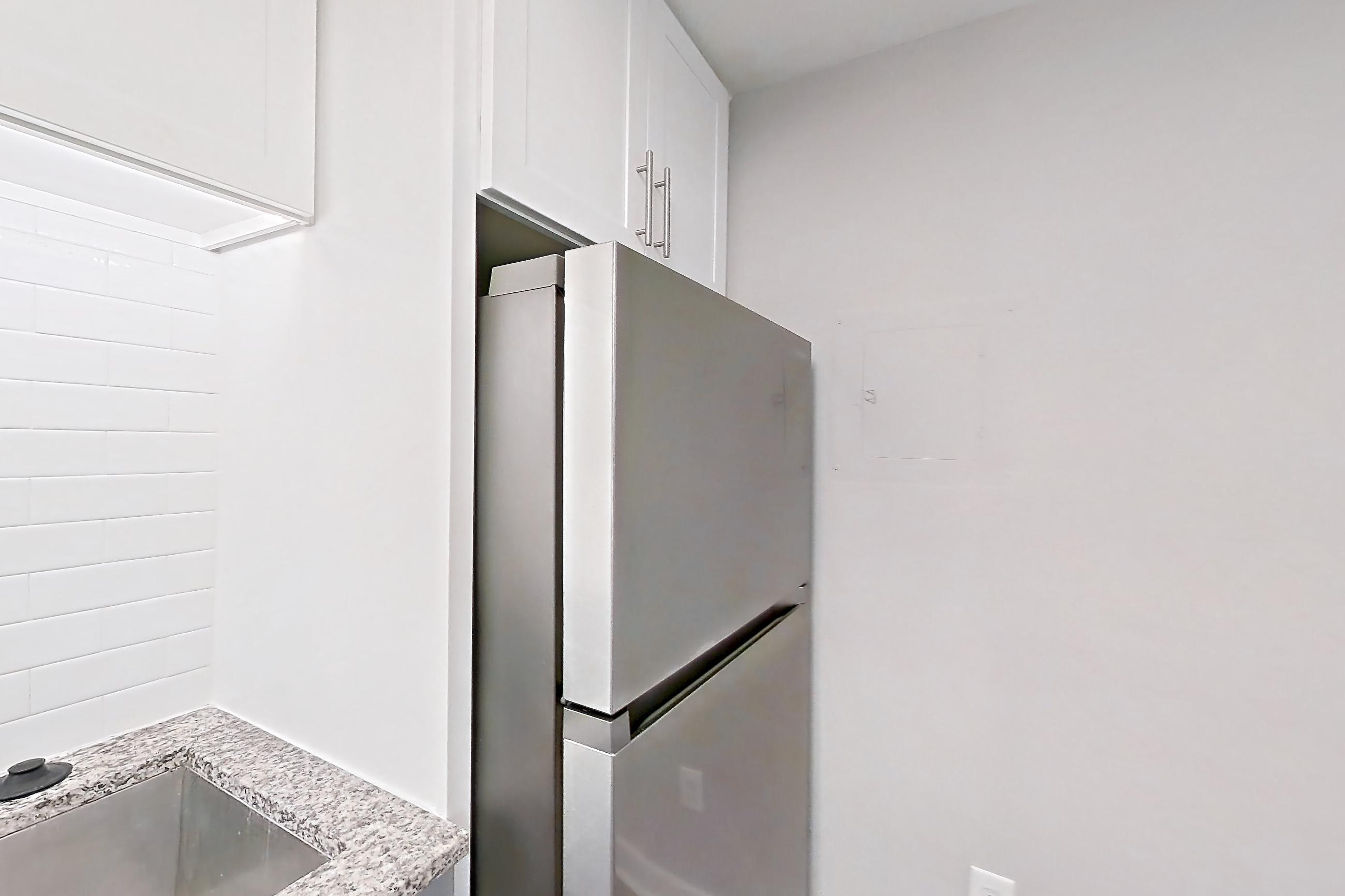 Kitchen with dark wood-finish flooring, dishwasher, electric range, light countertops, light stone countertops, microwave, oven/range, refrigerator, and stainless steel appliances, Apartment 2065Q at Cortland at the Village