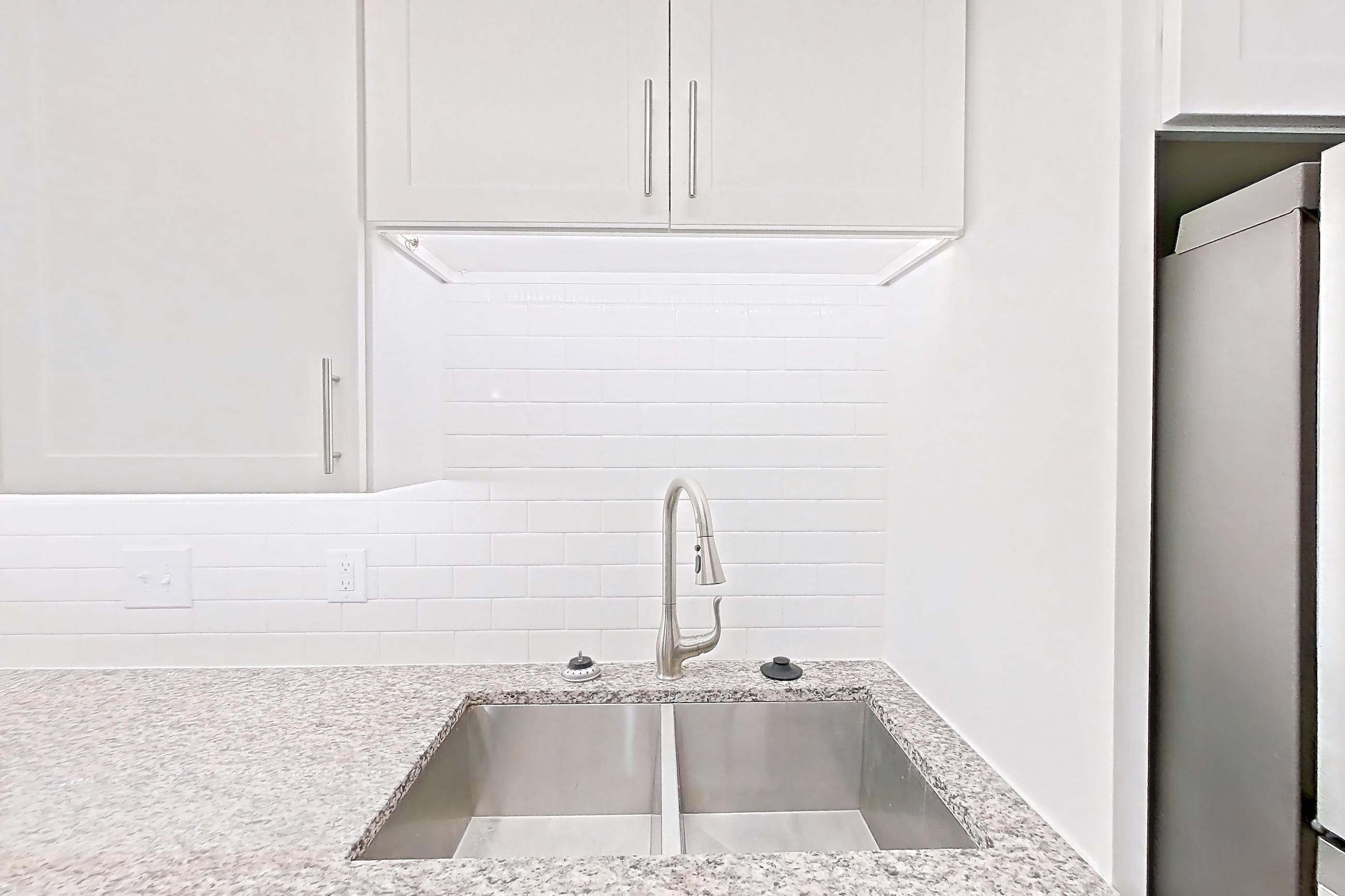 Kitchen with dark wood-finish flooring, dishwasher, electric range, light countertops, light stone countertops, microwave, oven/range, refrigerator, and stainless steel appliances, Apartment 2065Q at Cortland at the Village