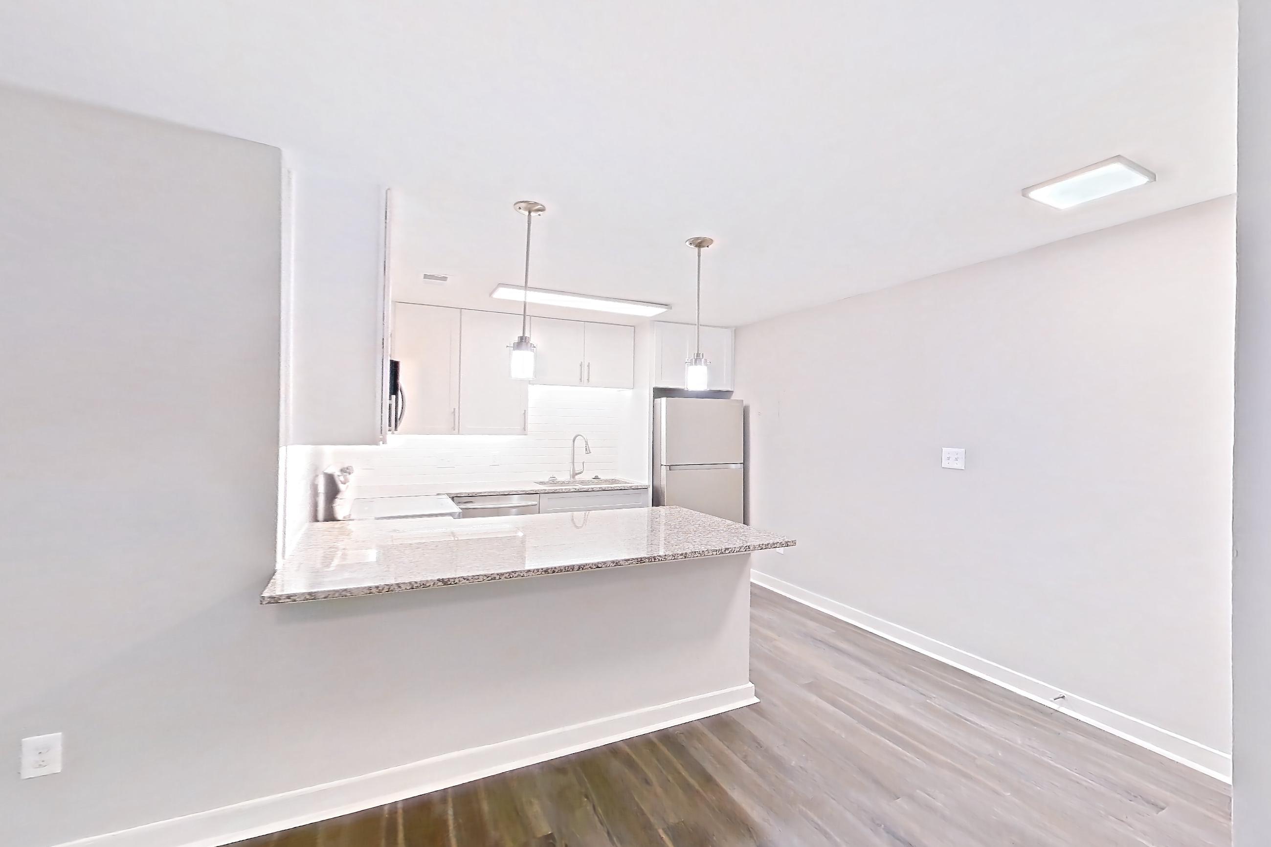 Living room with dark wood-finish flooring, dishwasher, refrigerator, stainless steel appliances, and white appliances, Apartment 2065Q at Cortland at the Village