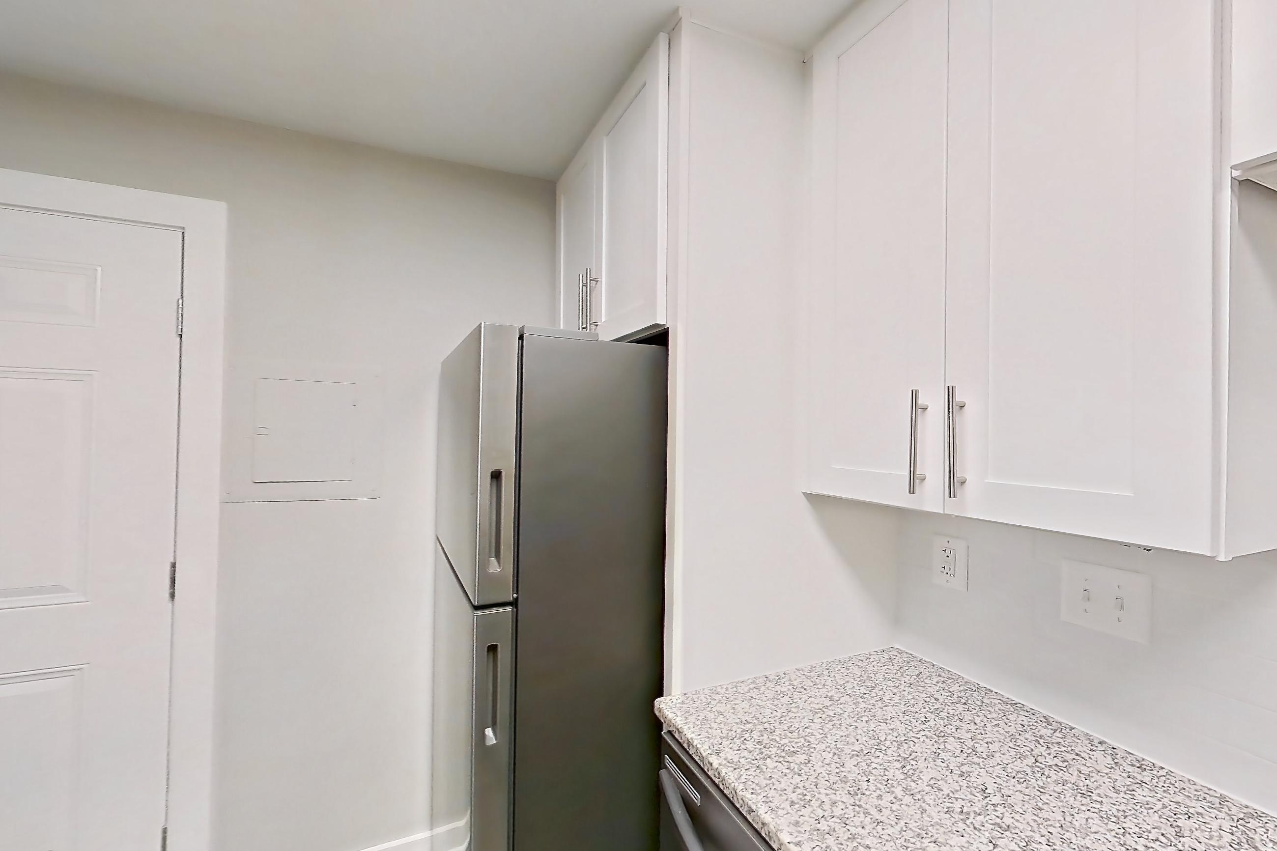 Kitchen with dishwasher, electric range, light countertops, light stone countertops, light wood-finish flooring, microwave, oven/range, refrigerator, and stainless steel appliances, Apartment 2083N at Cortland at the Village