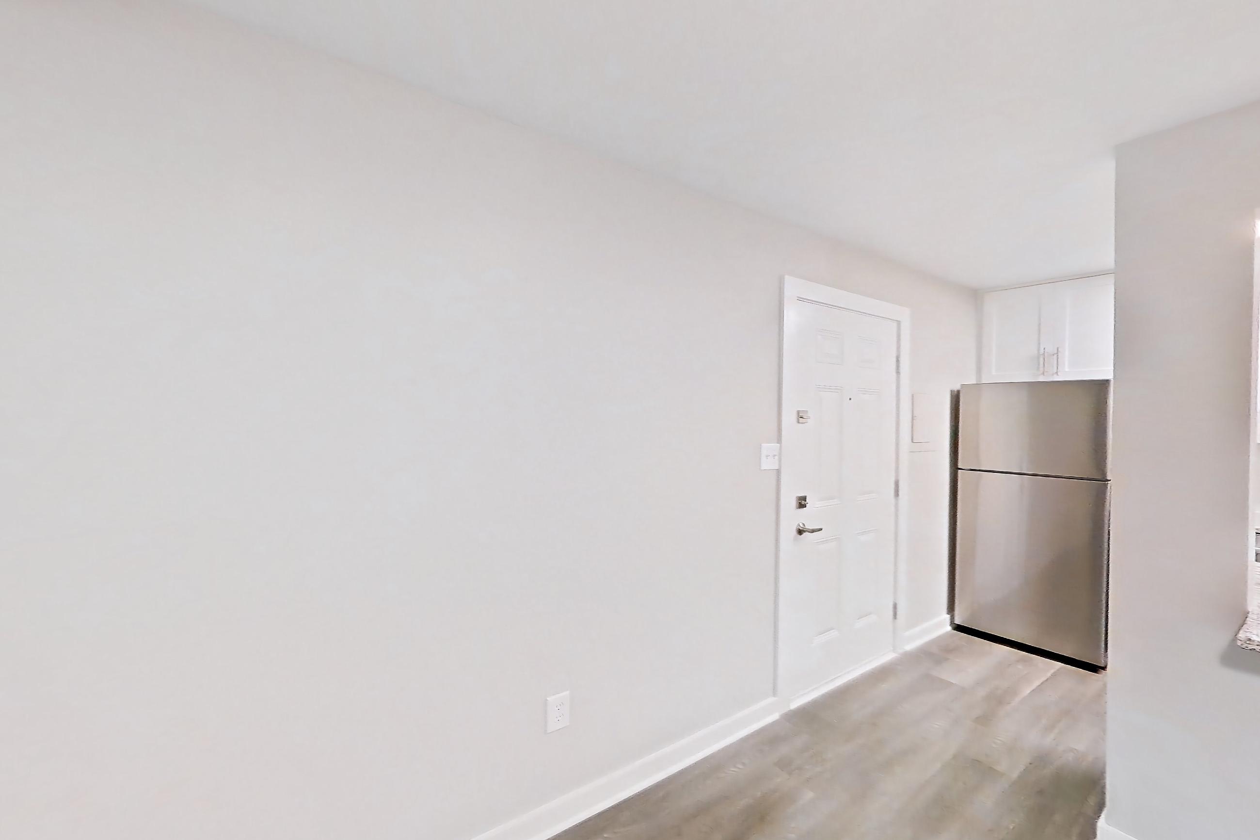 Living room with dark wood-finish flooring, light wood-finish flooring, refrigerator, and stainless steel appliances, Apartment 2083N at Cortland at the Village
