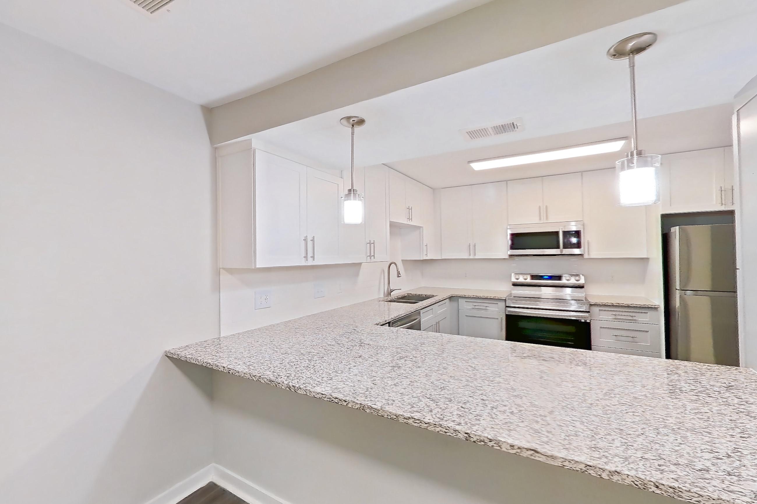 Dining room with dark wood-finish flooring, dishwasher, electric range, light countertops, light stone countertops, oven/range, refrigerator, and stainless steel appliances, Apartment 2141O at Cortland at the Village