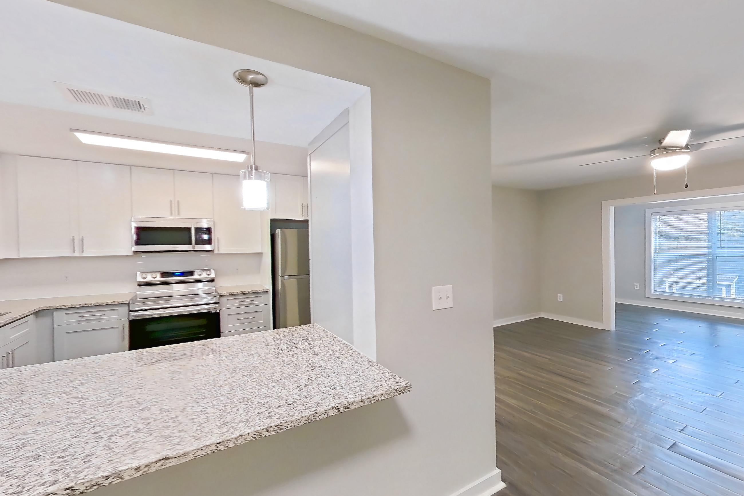 Dining room with dark wood-finish flooring, dishwasher, electric range, light countertops, light stone countertops, oven/range, refrigerator, and stainless steel appliances, Apartment 2141O at Cortland at the Village
