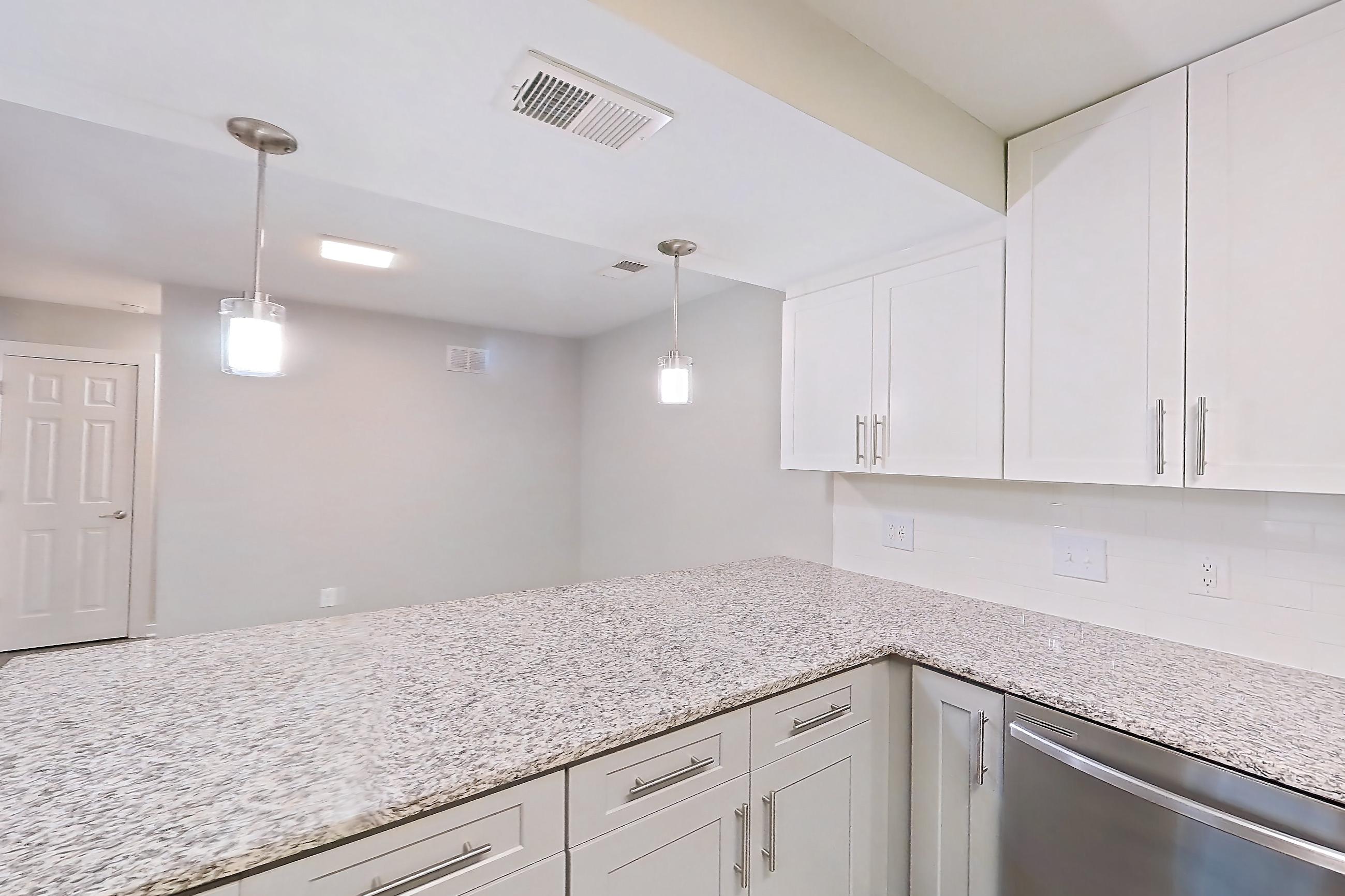 Kitchen with dark wood-finish flooring, dishwasher, electric range, light countertops, light stone countertops, light wood-finish flooring, microwave, oven/range, refrigerator, and stainless steel appliances, Apartment 2141O at Cortland at the Village