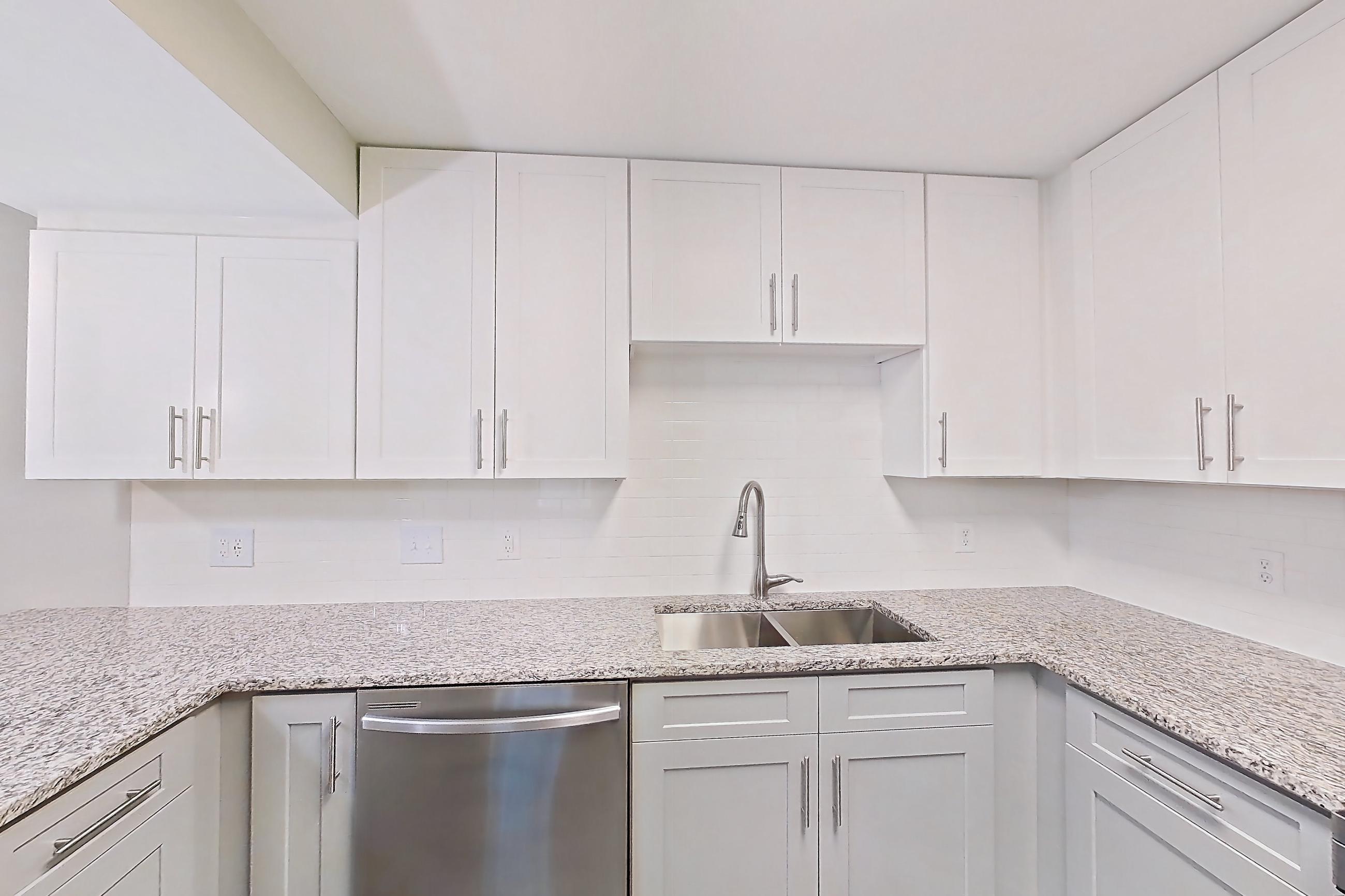 Kitchen with dark wood-finish flooring, dishwasher, electric range, light countertops, light stone countertops, light wood-finish flooring, microwave, oven/range, refrigerator, and stainless steel appliances, Apartment 2141O at Cortland at the Village