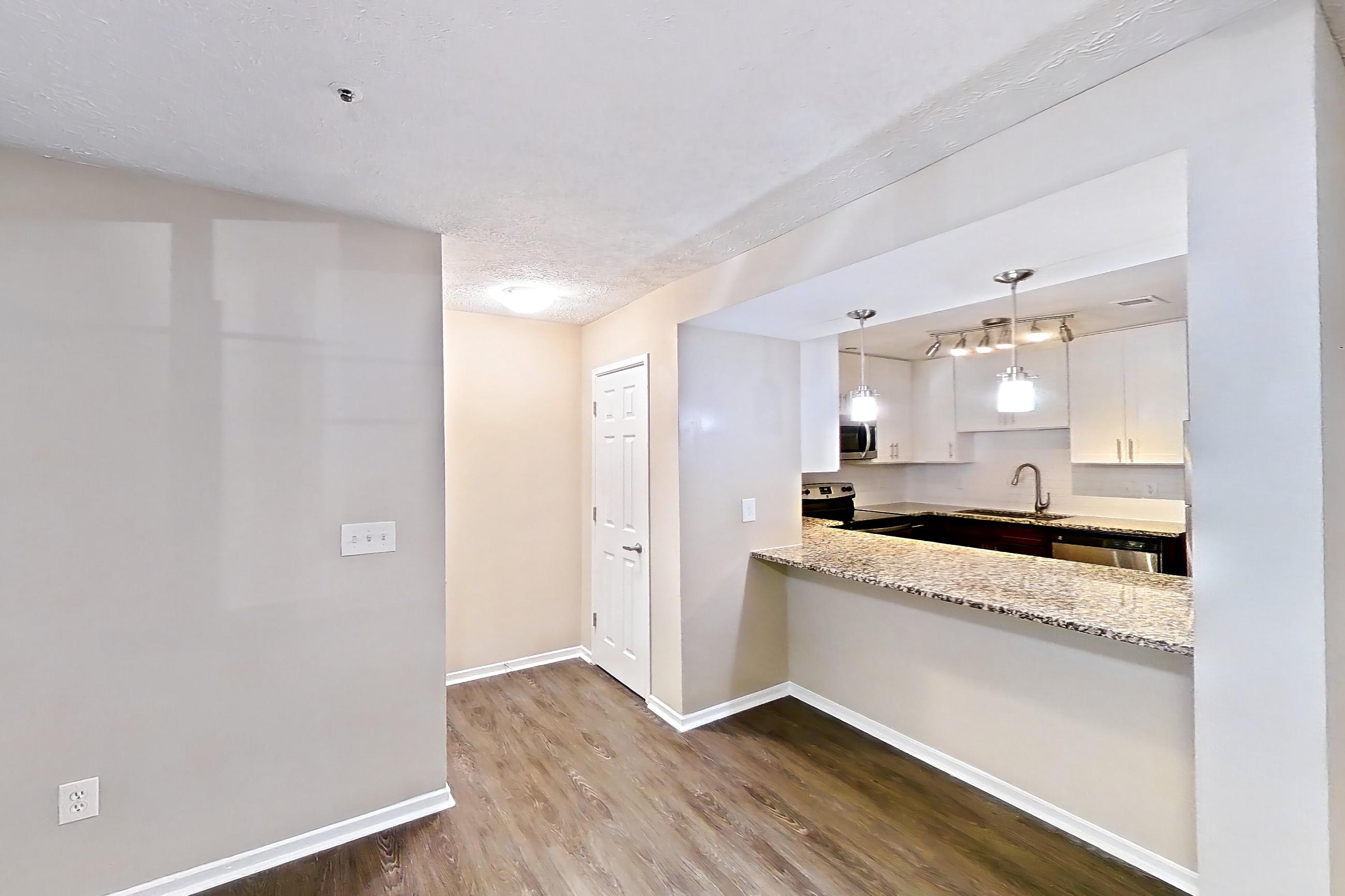 Living room with dark wood-finish flooring, dishwasher, electric range, oven/range, and stainless steel appliances, Apartment 2161D at Cortland at the Village