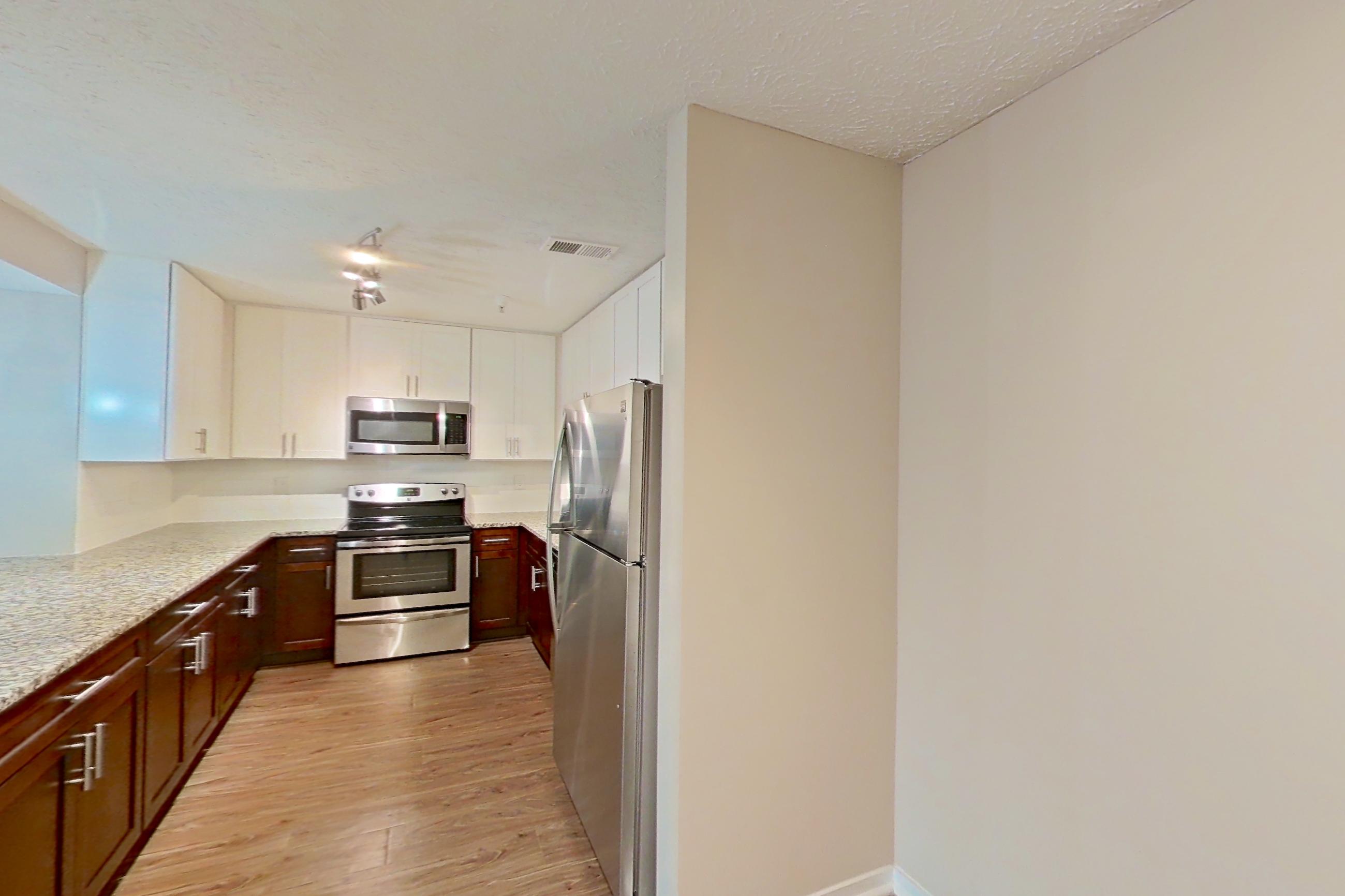 Dining room with electric range, light countertops, light stone countertops, light wood-finish flooring, oven/range, refrigerator, and stainless steel appliances, Apartment 2163L at Cortland at the Village