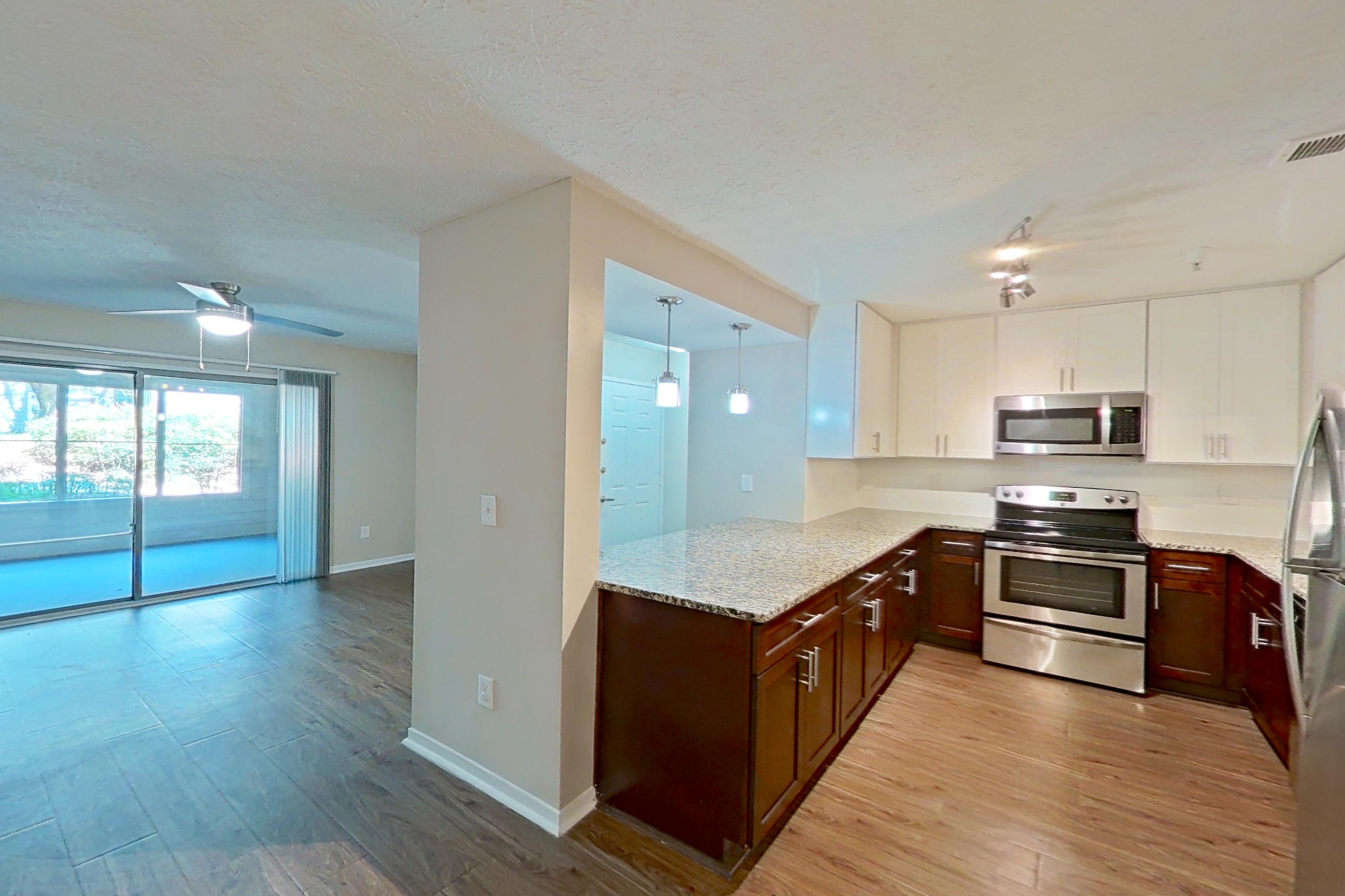 Dining room with electric range, light countertops, light stone countertops, light wood-finish flooring, oven/range, refrigerator, and stainless steel appliances, Apartment 2163L at Cortland at the Village