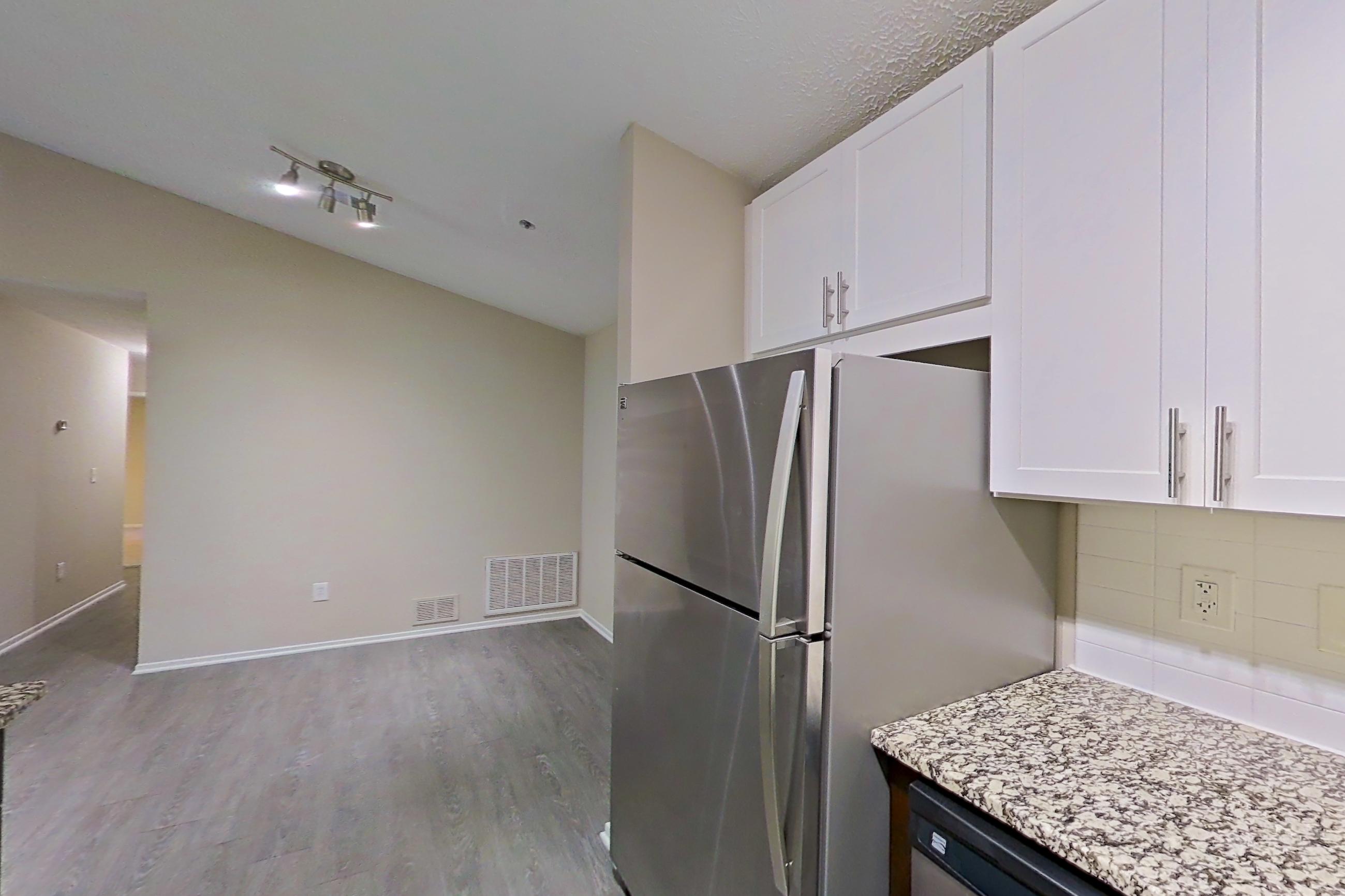 Kitchen with electric range, light countertops, light stone countertops, light wood-finish flooring, microwave, oven/range, refrigerator, and stainless steel appliances, Apartment 2165S at Cortland at the Village