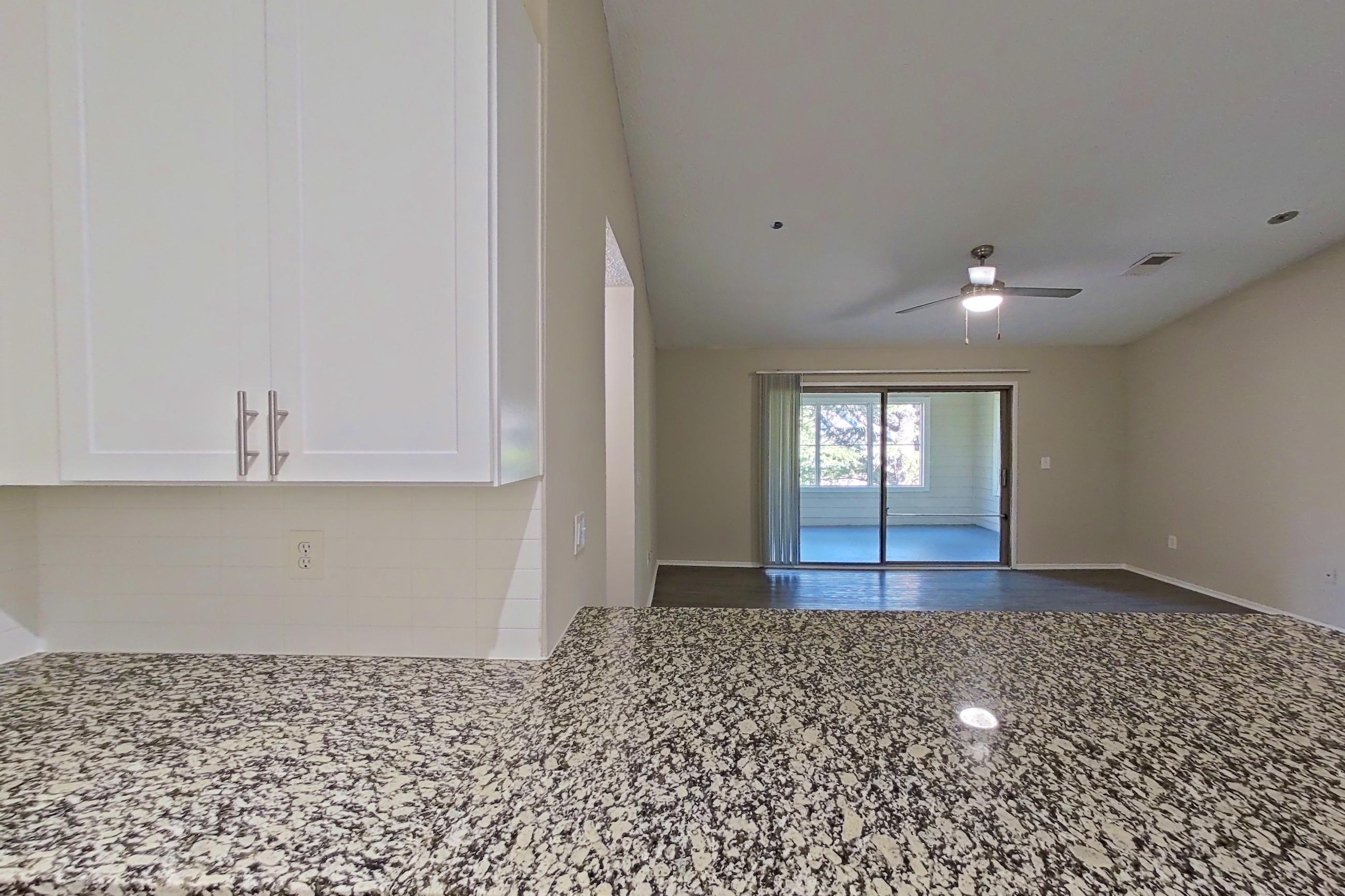 Kitchen with electric range, light countertops, light stone countertops, light wood-finish flooring, microwave, oven/range, refrigerator, and stainless steel appliances, Apartment 2165S at Cortland at the Village
