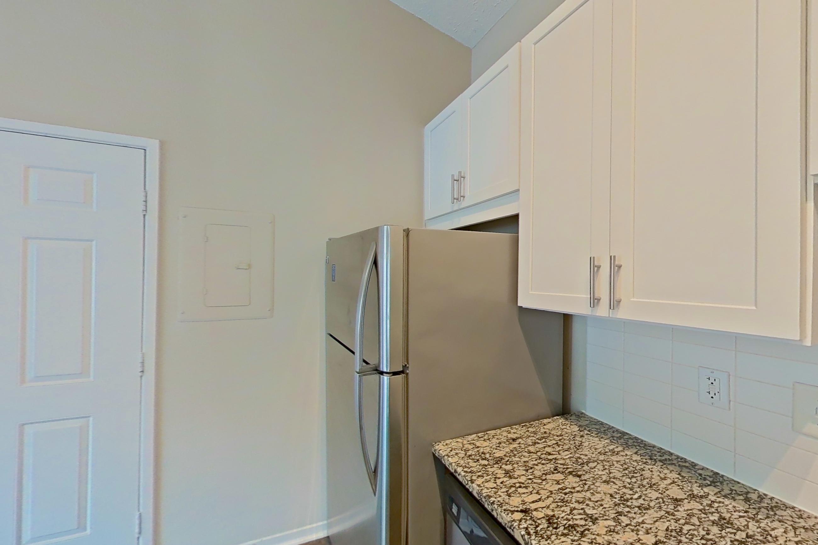 Kitchen with dishwasher, electric range, light countertops, light stone countertops, light wood-finish flooring, microwave, oven/range, refrigerator, and stainless steel appliances, Apartment 2167L at Cortland at the Village