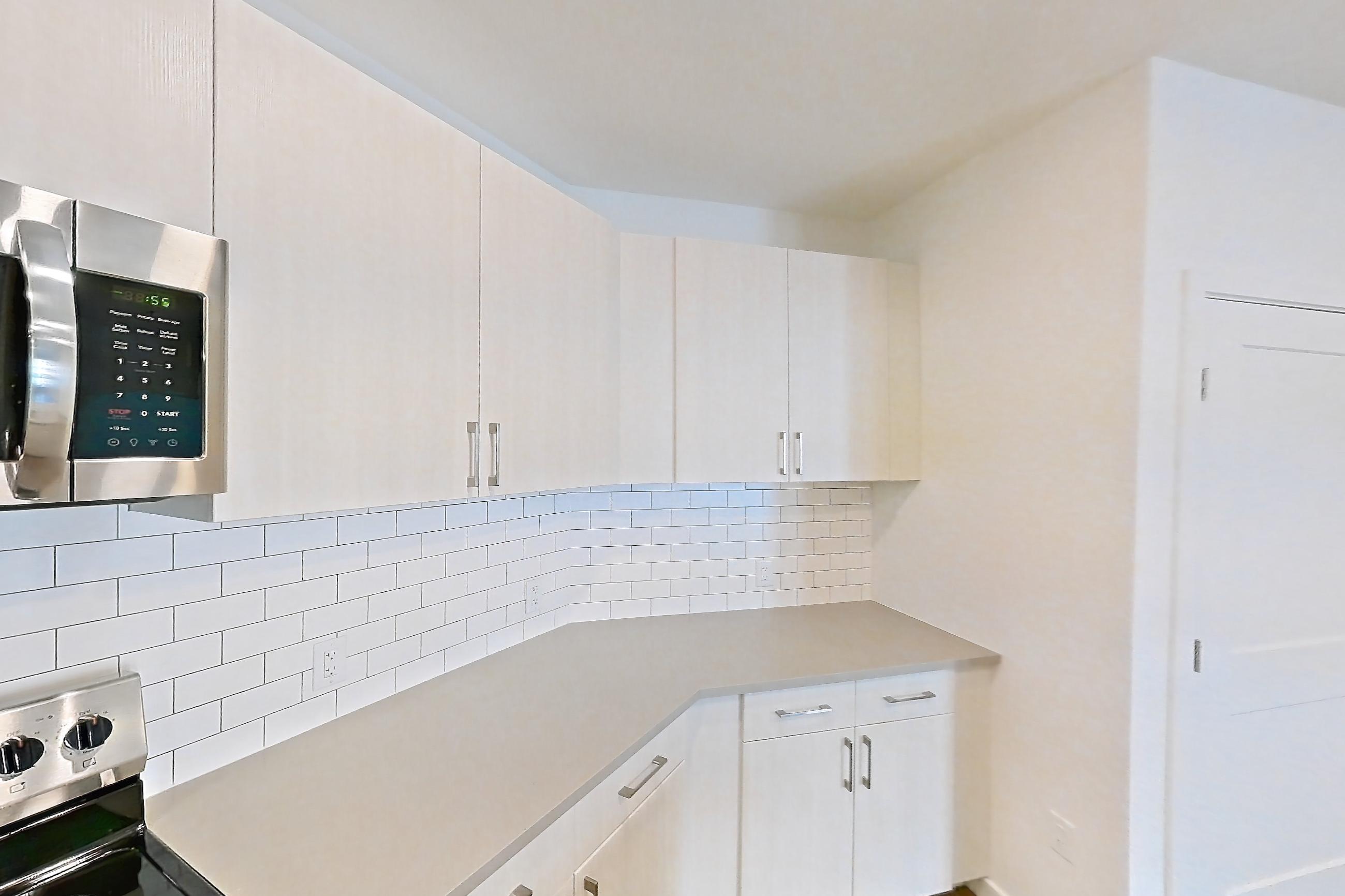 Kitchen with dishwasher, electric range, light countertops, light wood-finish flooring, microwave, oven/range, refrigerator, and stainless steel appliances, Apartment 425 at Braxton