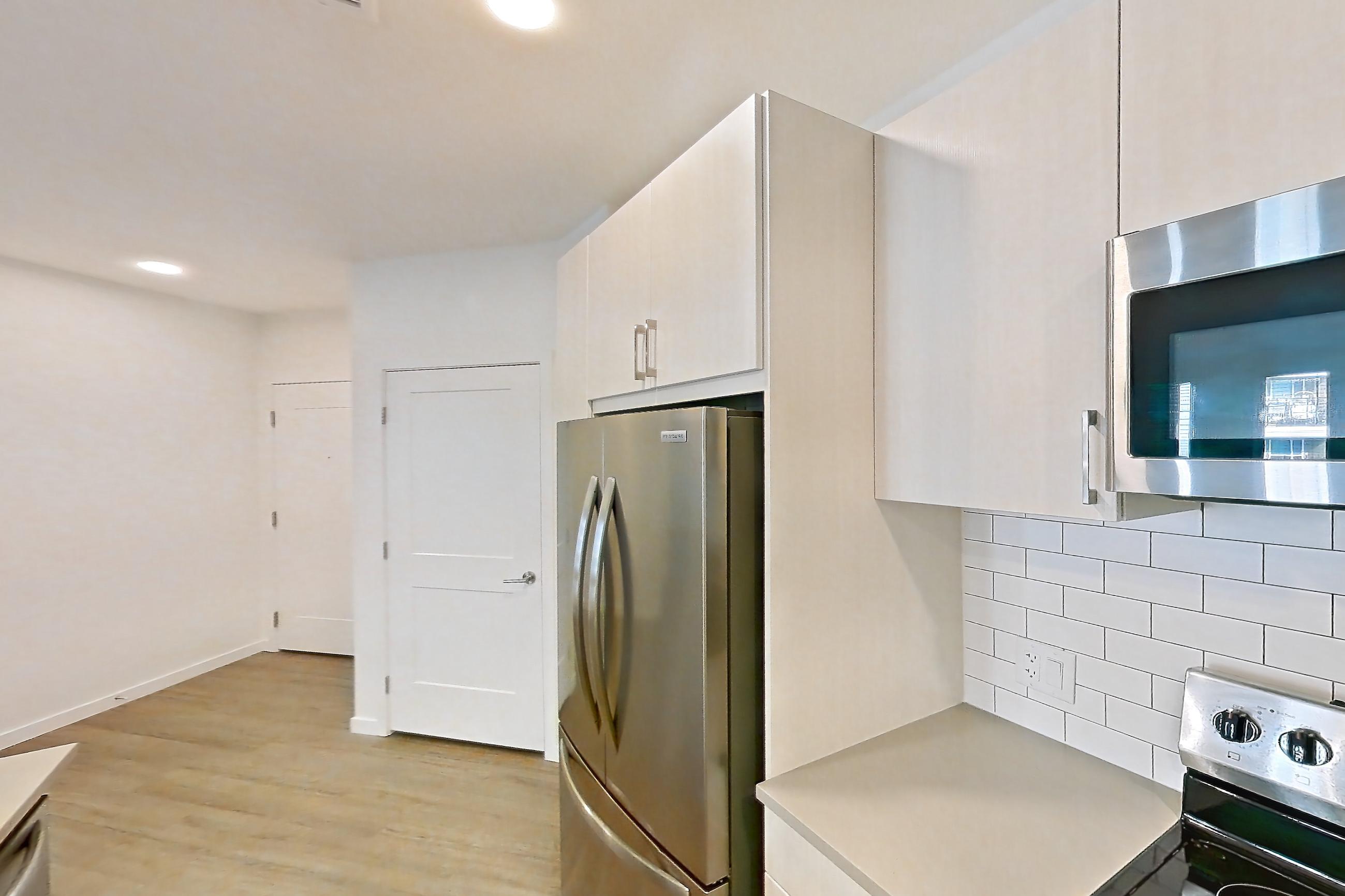 Kitchen with dishwasher, electric range, light countertops, light wood-finish flooring, microwave, oven/range, refrigerator, and stainless steel appliances, Apartment 425 at Braxton