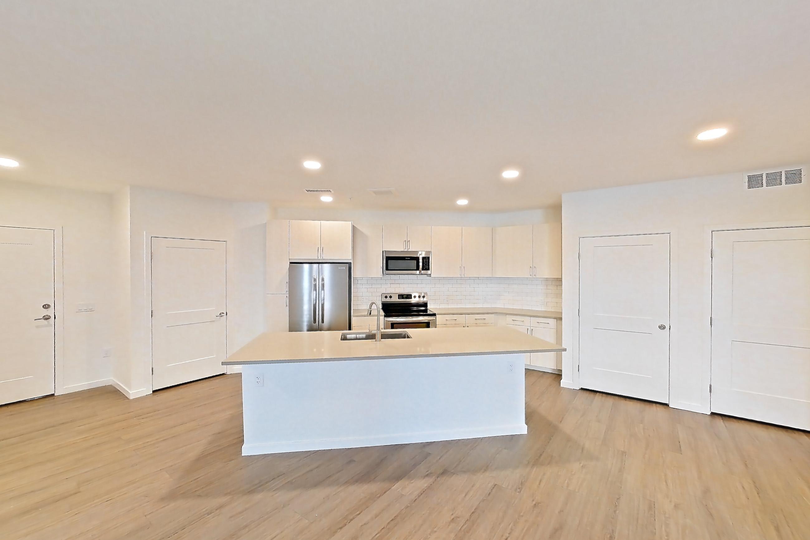 Living space with electric range, kitchen island, light countertops, light wood-finish flooring, oven/range, refrigerator, and stainless steel appliances, Apartment 425 at Braxton