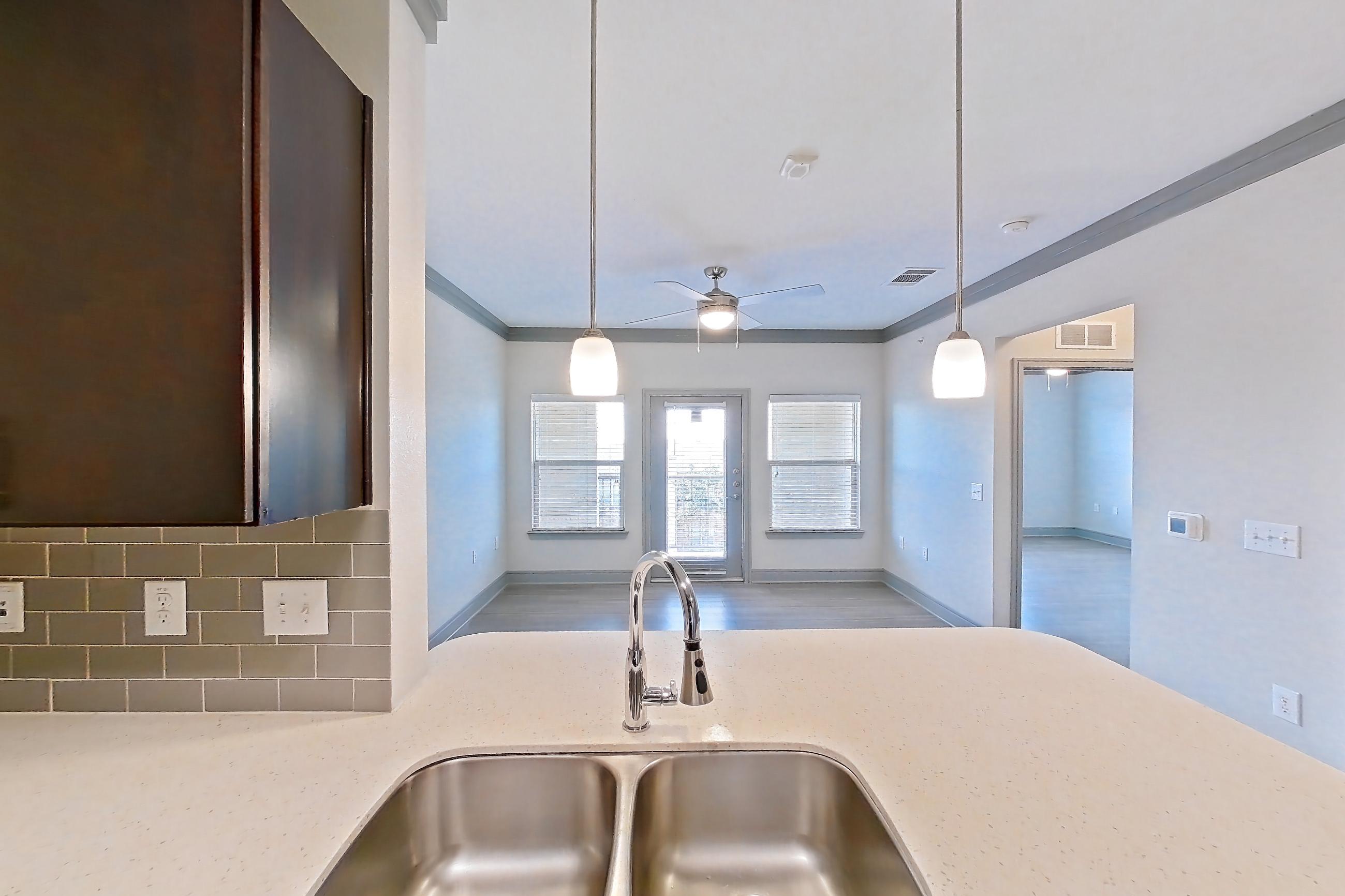 Kitchen with electric range, light stone countertops, light wood-finish flooring, oven/range, refrigerator, and stainless steel appliances, Apartment 2309 at Cortland Phillips Creek Ranch