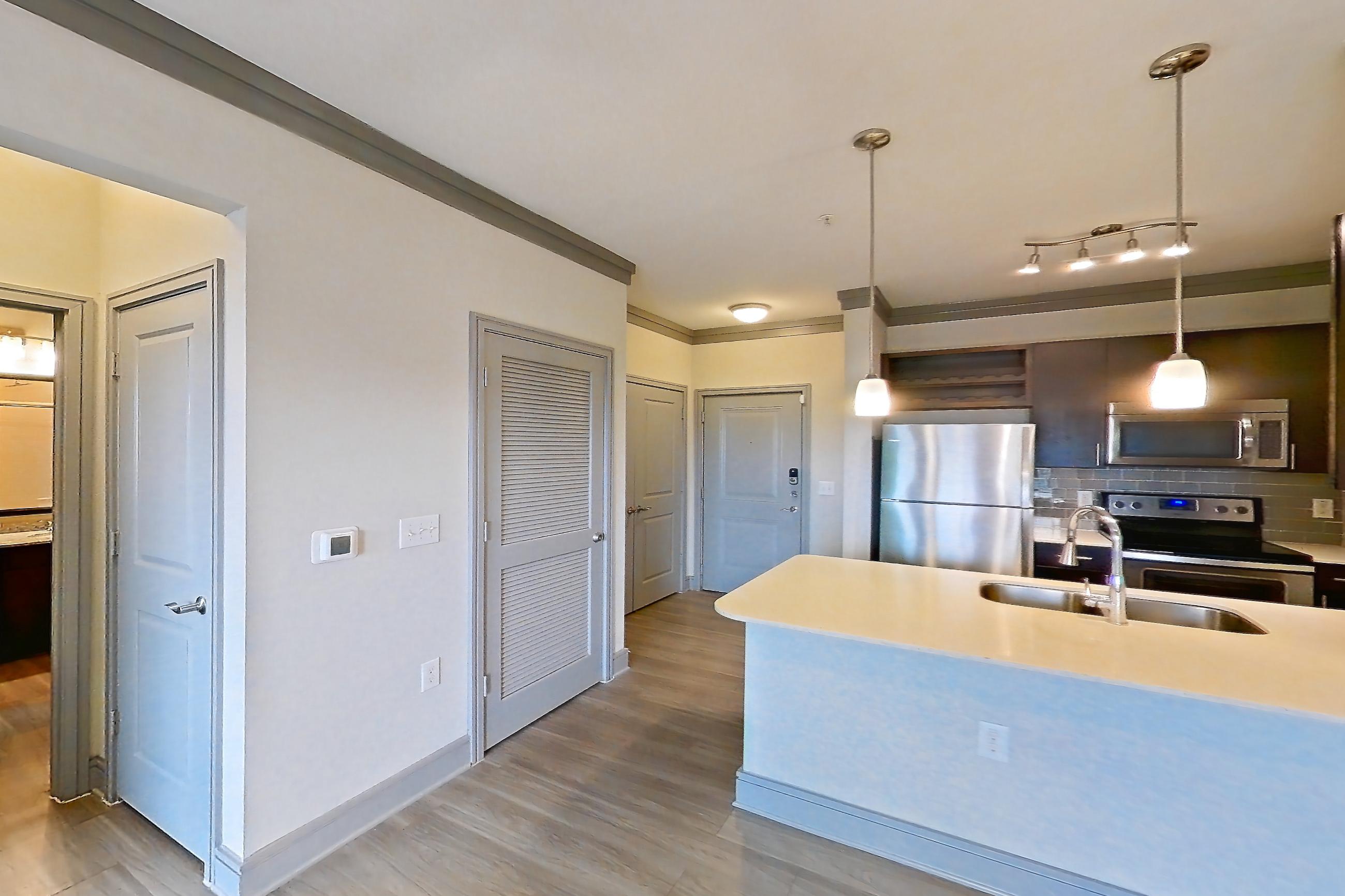 Living room with electric range, light countertops, light wood-finish flooring, oven/range, refrigerator, and stainless steel appliances, Apartment 2309 at Cortland Phillips Creek Ranch