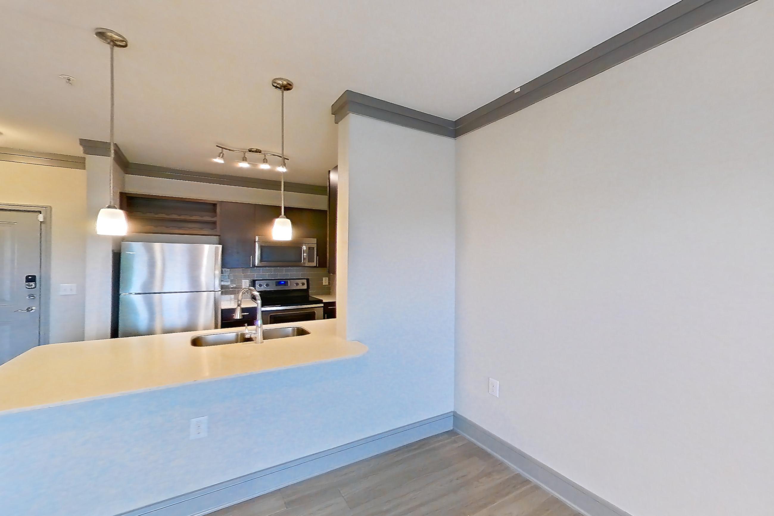 Living room with electric range, light countertops, light wood-finish flooring, oven/range, refrigerator, and stainless steel appliances, Apartment 2309 at Cortland Phillips Creek Ranch