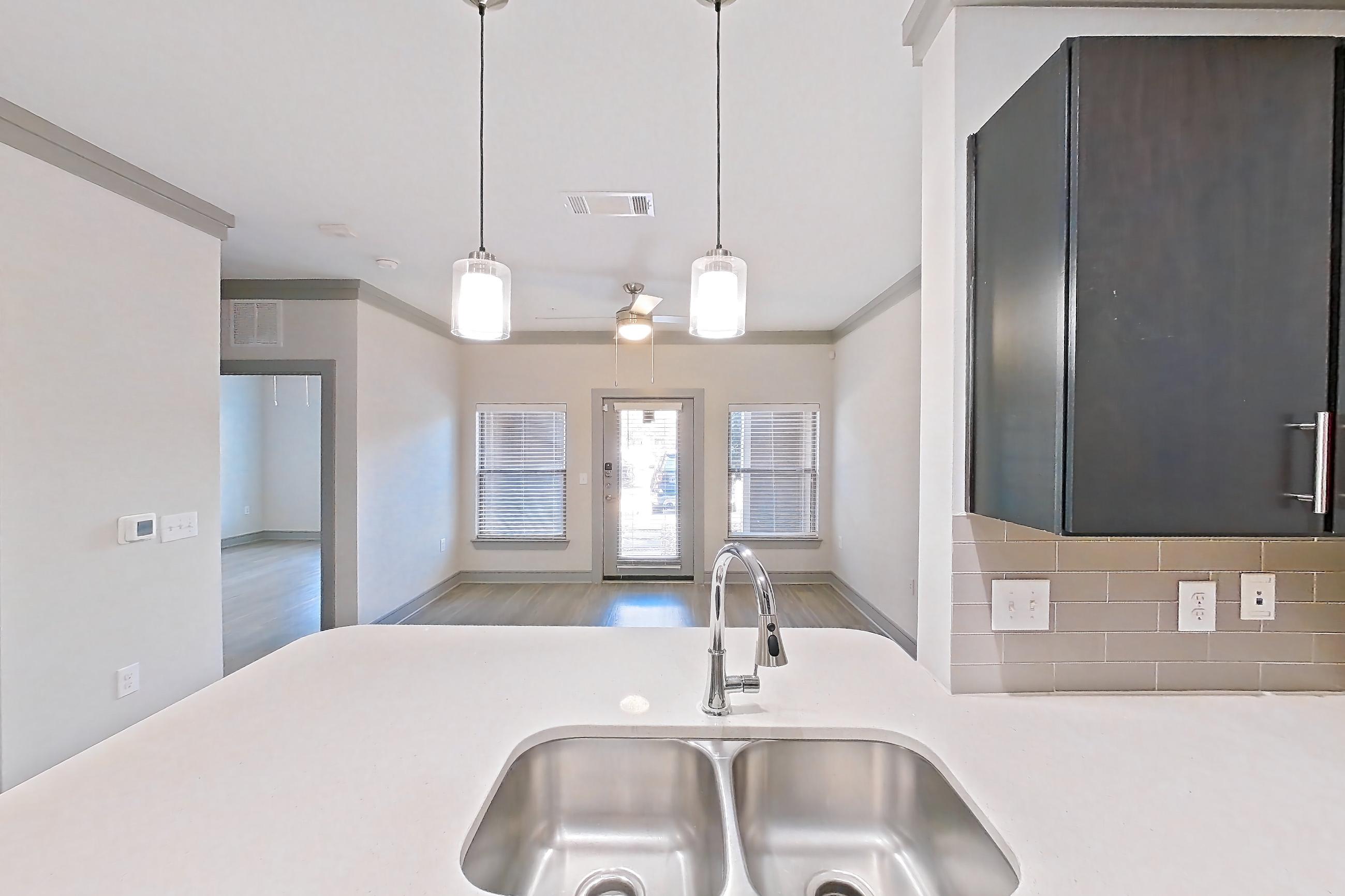 Kitchen with dishwasher, light stone countertops, light wood-finish flooring, oven/range, refrigerator, and stainless steel appliances, Apartment 18132 at Cortland Phillips Creek Ranch