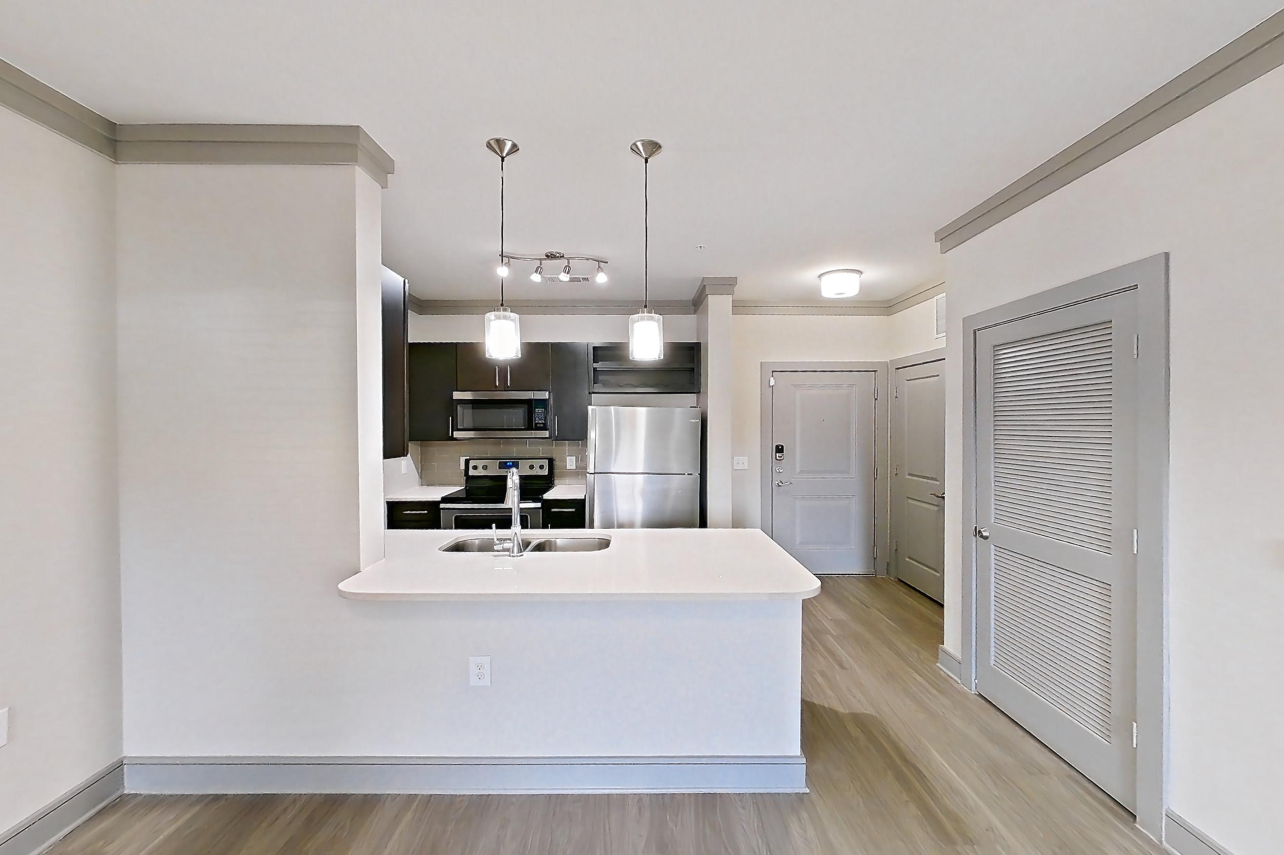 Living room with electric range, light countertops, light wood-finish flooring, oven/range, refrigerator, and stainless steel appliances, Apartment 18132 at Cortland Phillips Creek Ranch